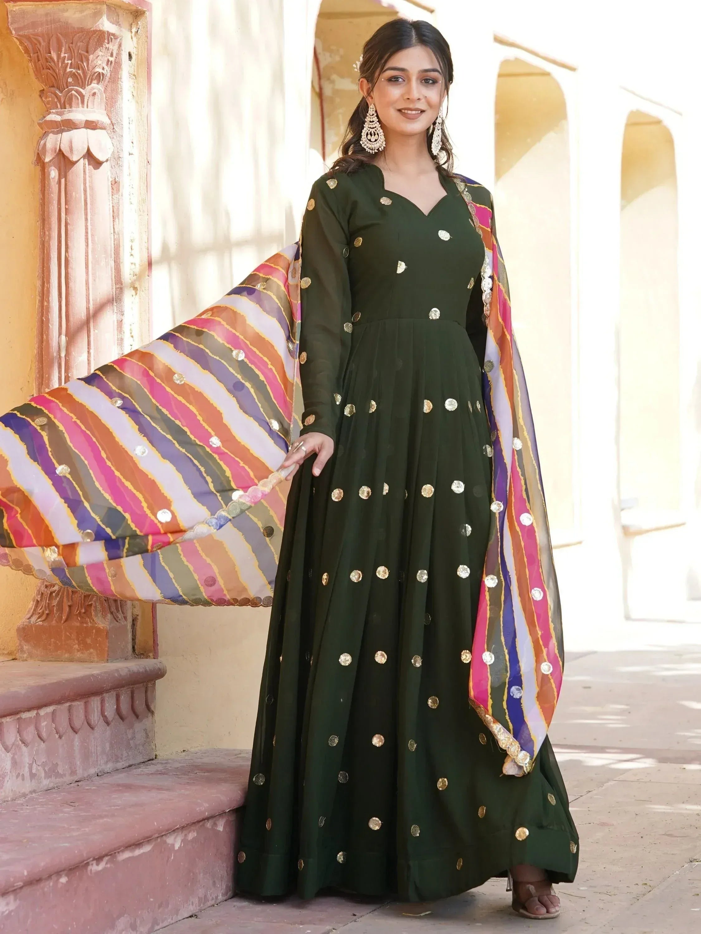 Purple ethnic gown with gold embellishments and colorful striped dupatta, perfect for Indian festive occasions.