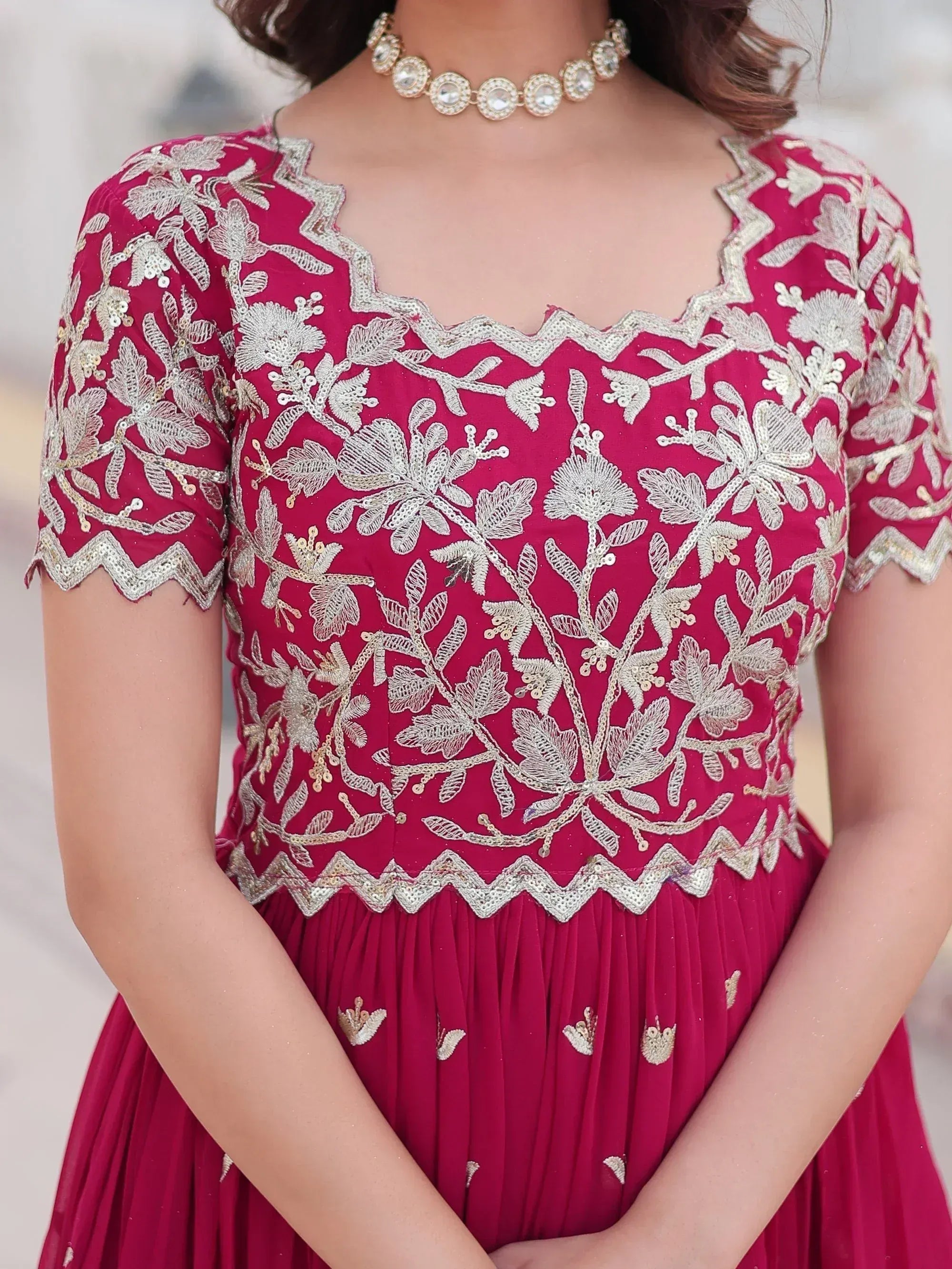 Elegant maroon ethnic gown with gold floral embroidery and scalloped neckline, perfect for Indian celebrations.