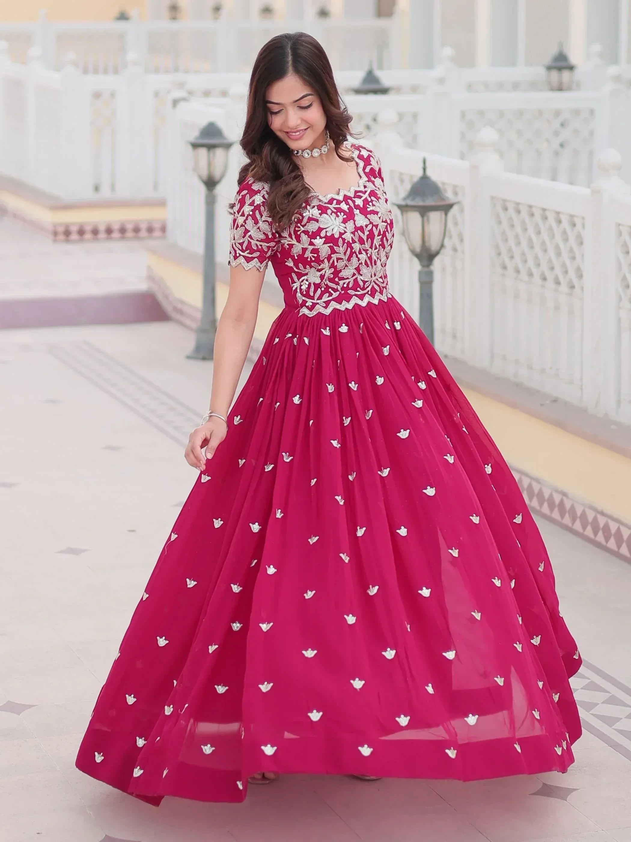 Woman in maroon ethnic gown with silver floral embroidery, perfect for Indian weddings or festive occasions.