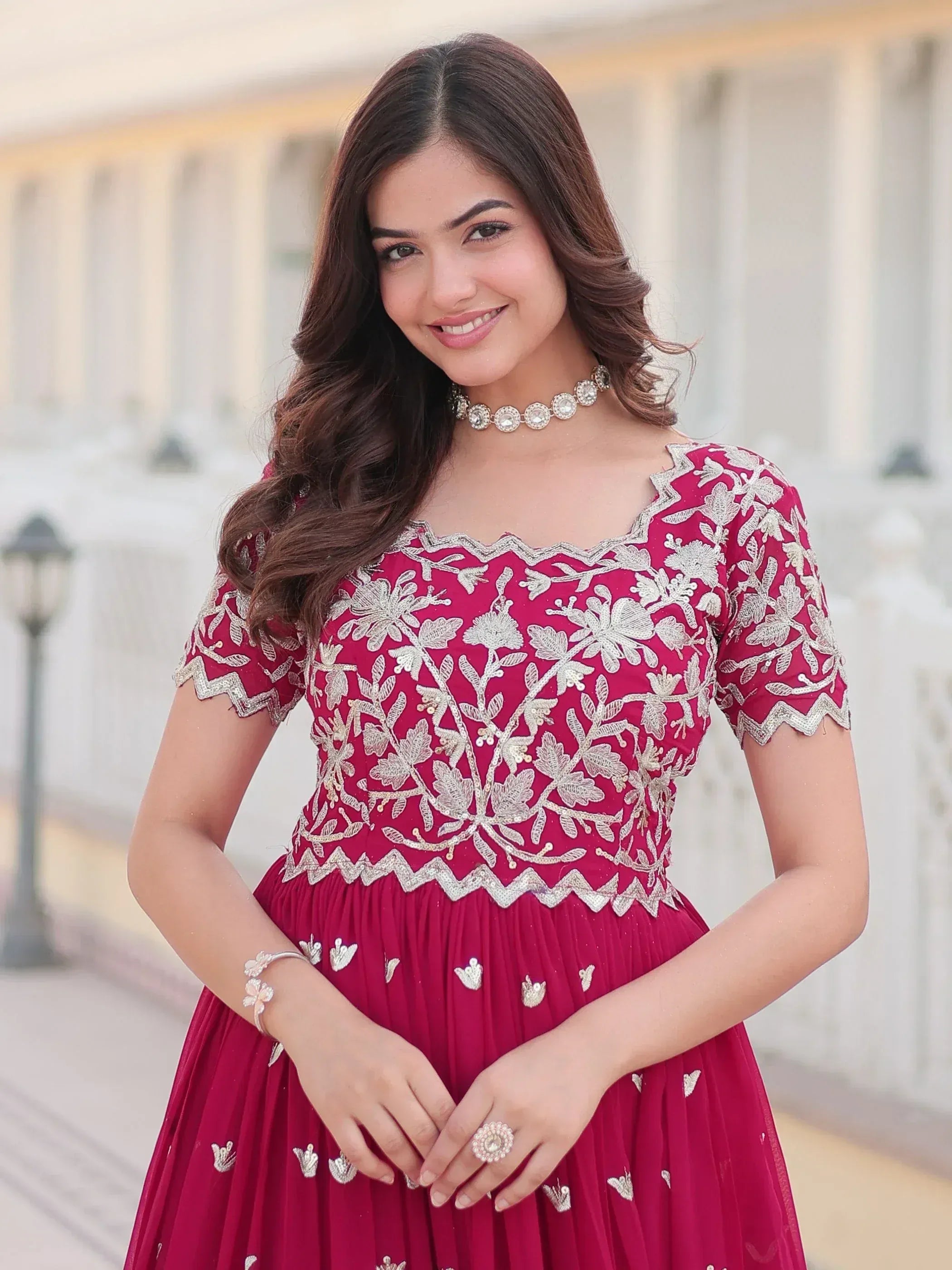 Woman in maroon ethnic gown with silver floral embroidery, perfect for Indian occasions and weddings.