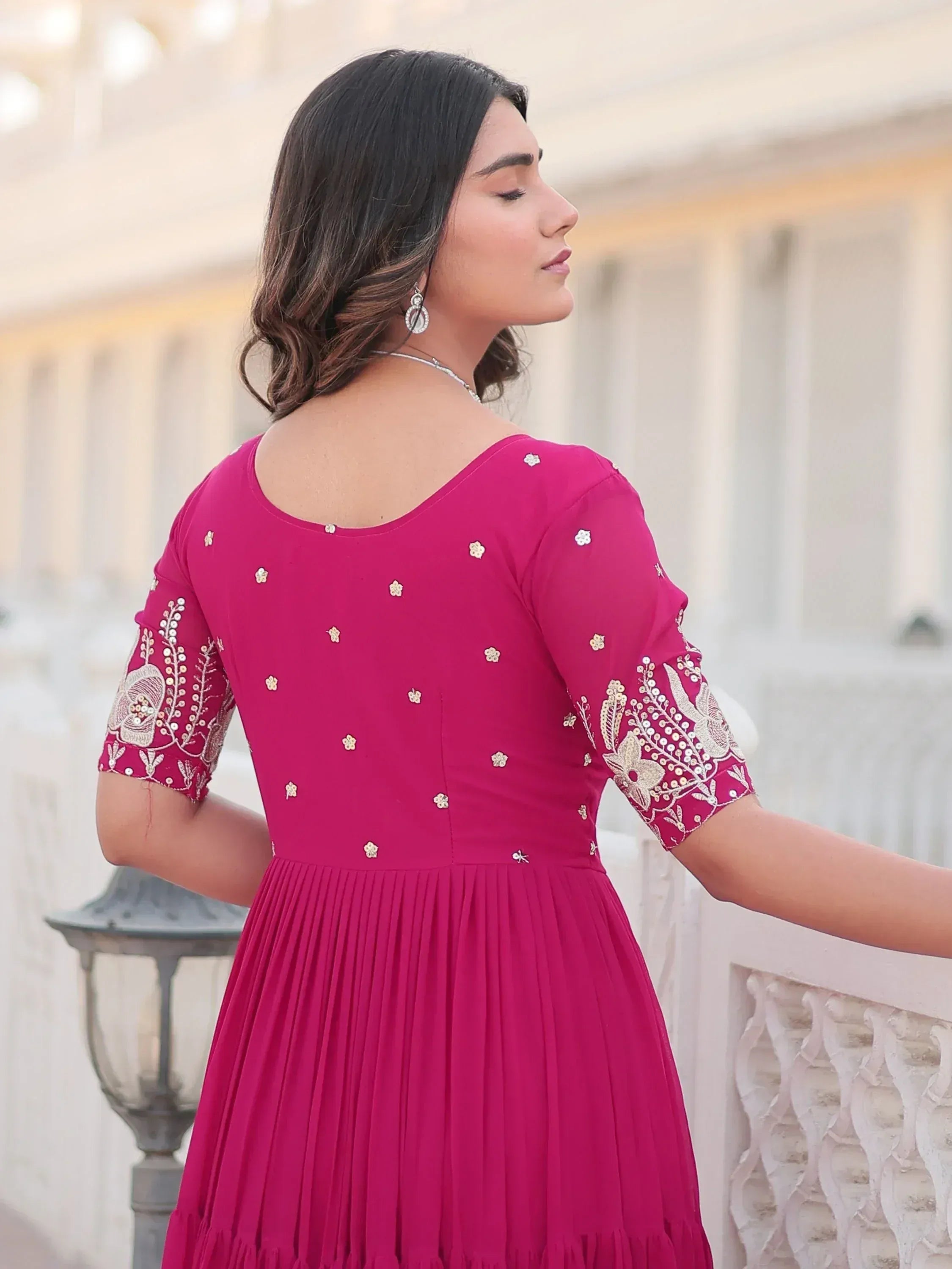Pink ethnic gown with gold embroidery, pleated skirt, and floral sleeve details for Indian occasions