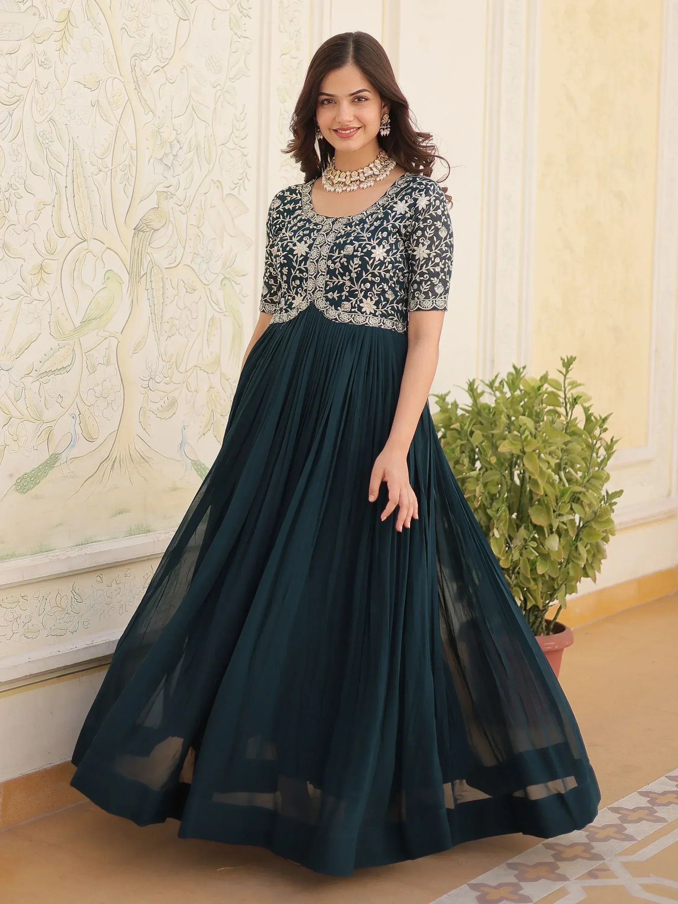 Elegant dark green ethnic gown with floral embroidery and pleated skirt, perfect for Indian occasions.