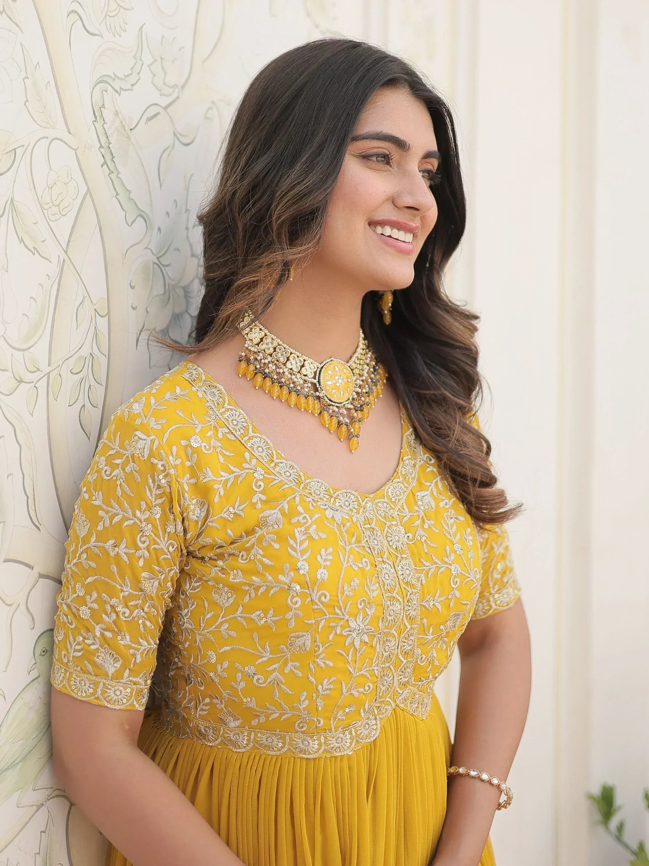 Yellow embroidered ethnic gown with floral detailing and matching jewelry for Indian wear