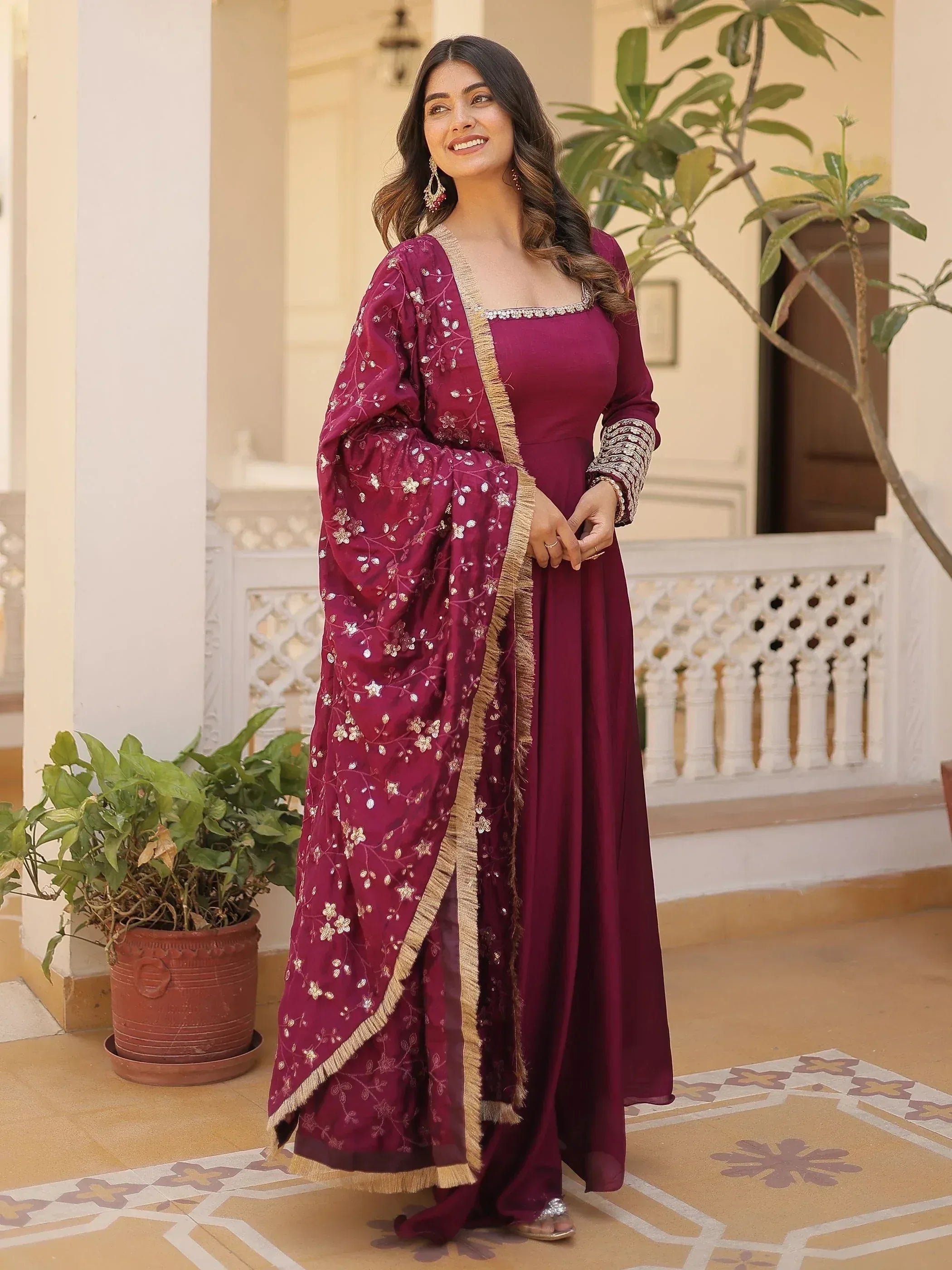 Elegant maroon ethnic gown with floral embroidery and gold trim, perfect for Indian celebrations