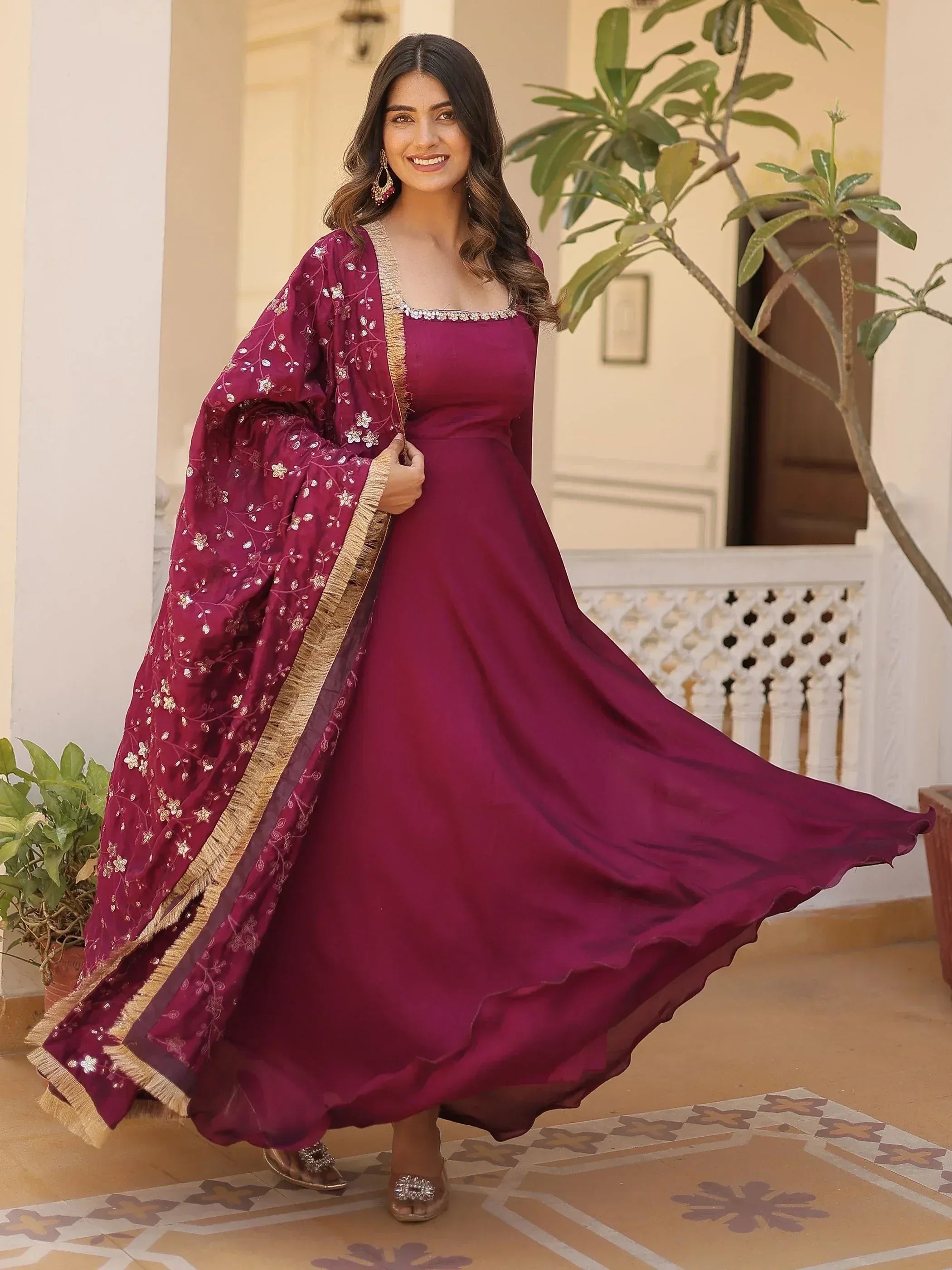 Elegant maroon ethnic gown with floral embroidery and gold trim, perfect for Indian celebrations