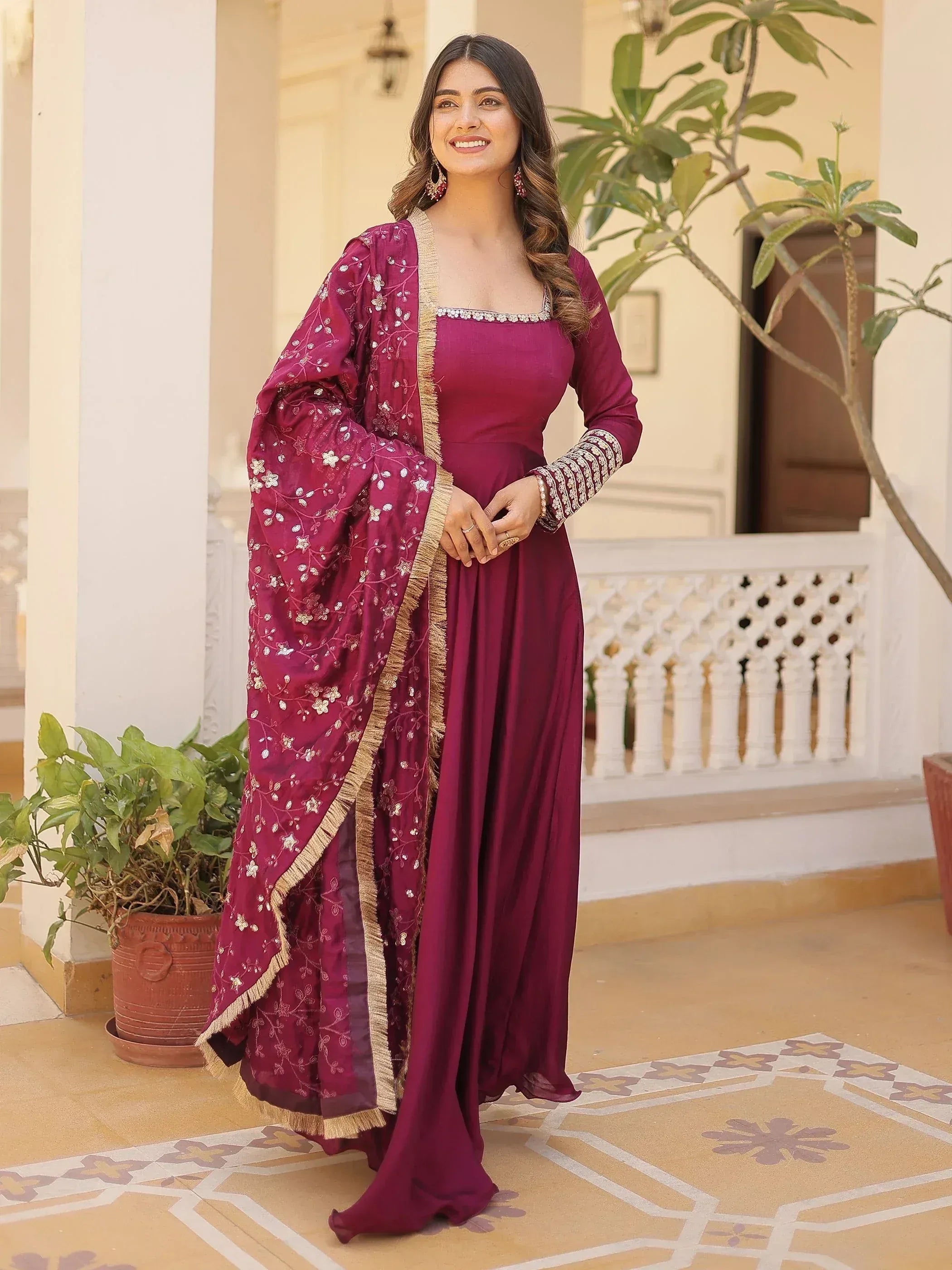 Elegant maroon ethnic gown with floral embroidery and gold trim, perfect for Indian occasions