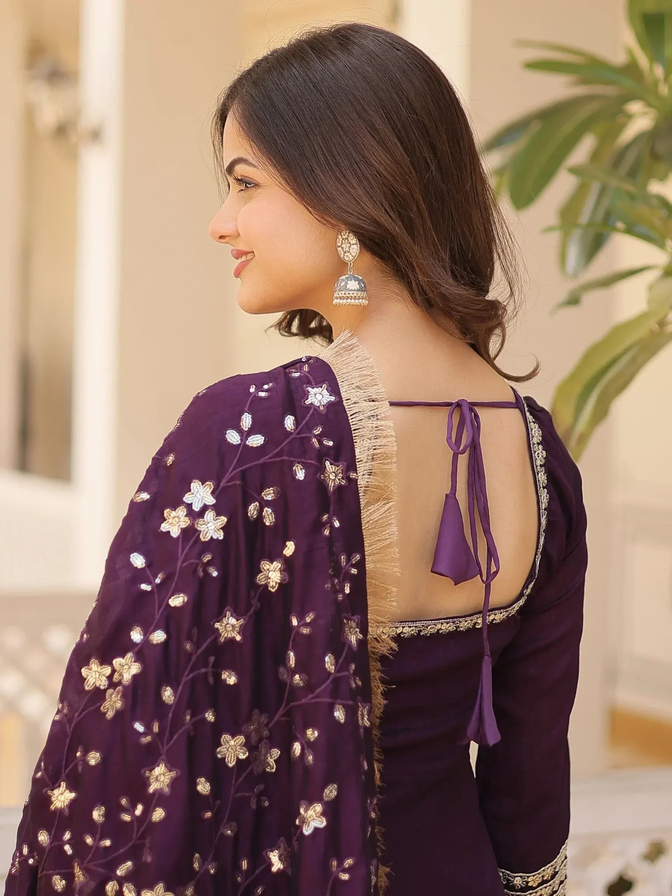 Purple embroidered ethnic gown with floral detailing and open back, paired with jhumka earrings