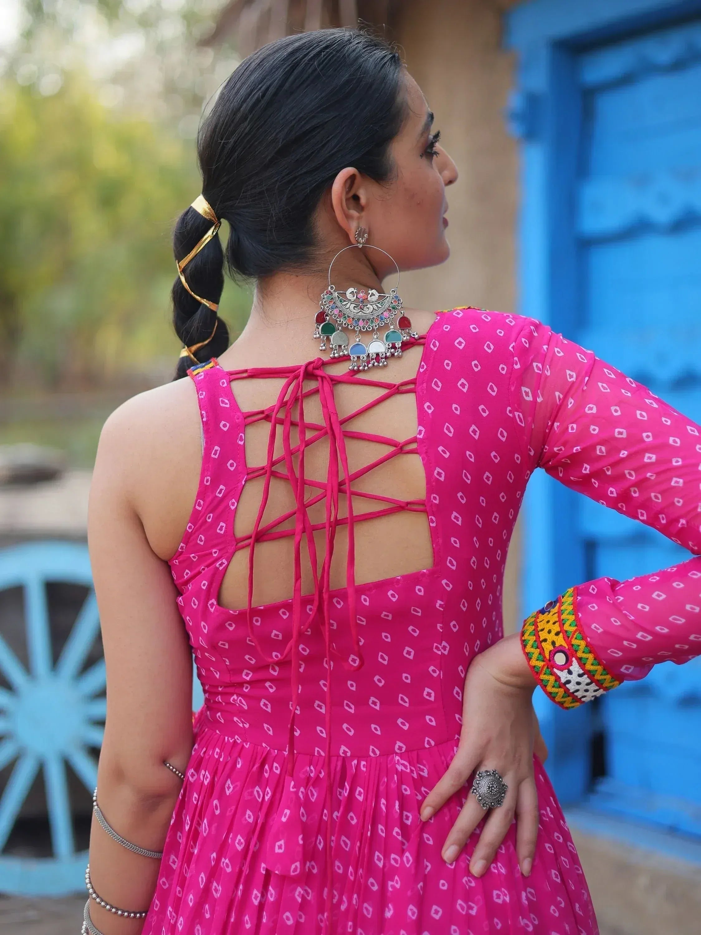 Pink ethnic gown with back crisscross ties, mirror work, and traditional jewelry for Indian wear