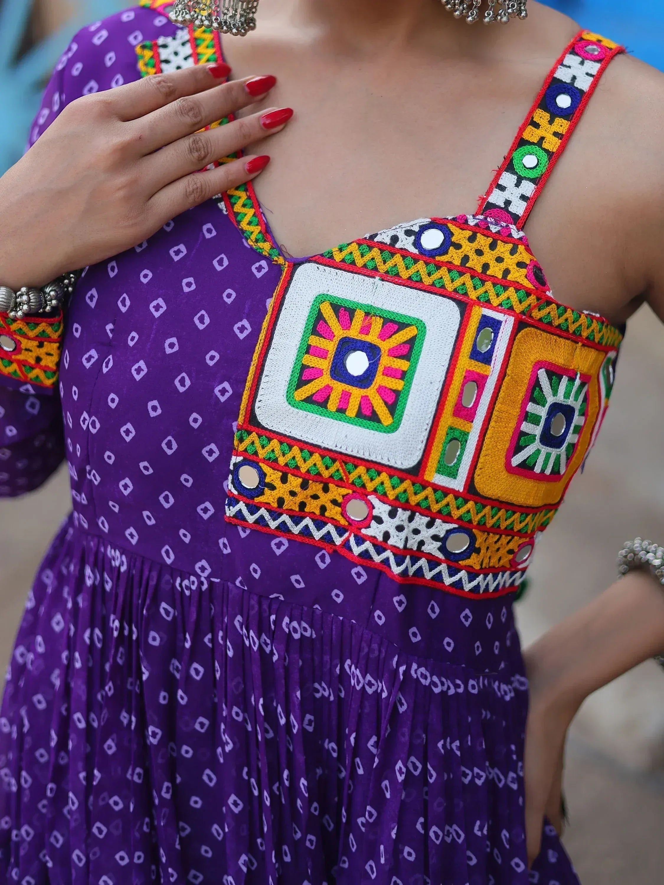 Purple ethnic gown with vibrant mirror work and geometric embroidery, perfect for festive occasions.