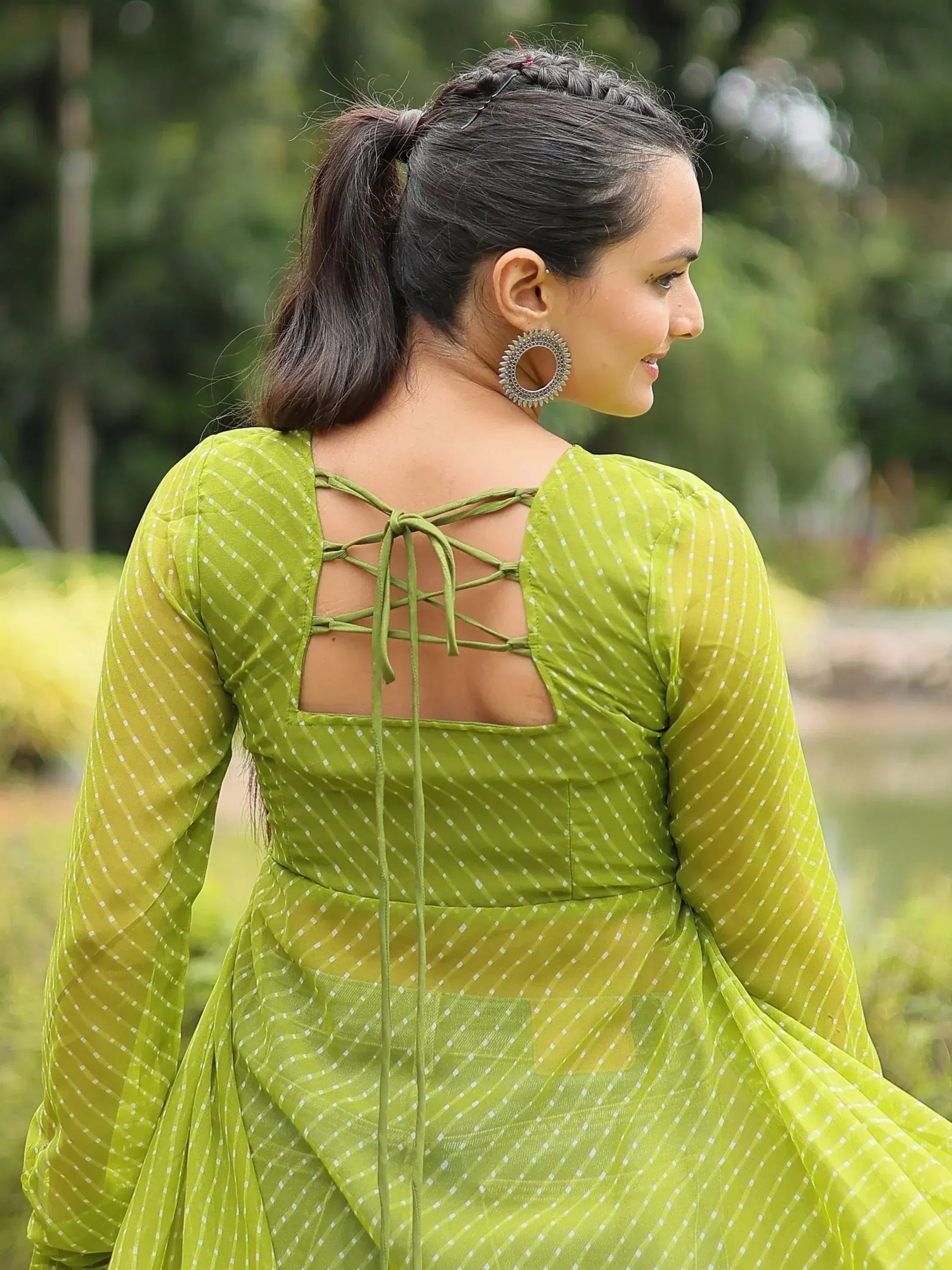 Green polka dot ethnic gown with back lace-up detail, styled with jhumka earrings for festive occasions