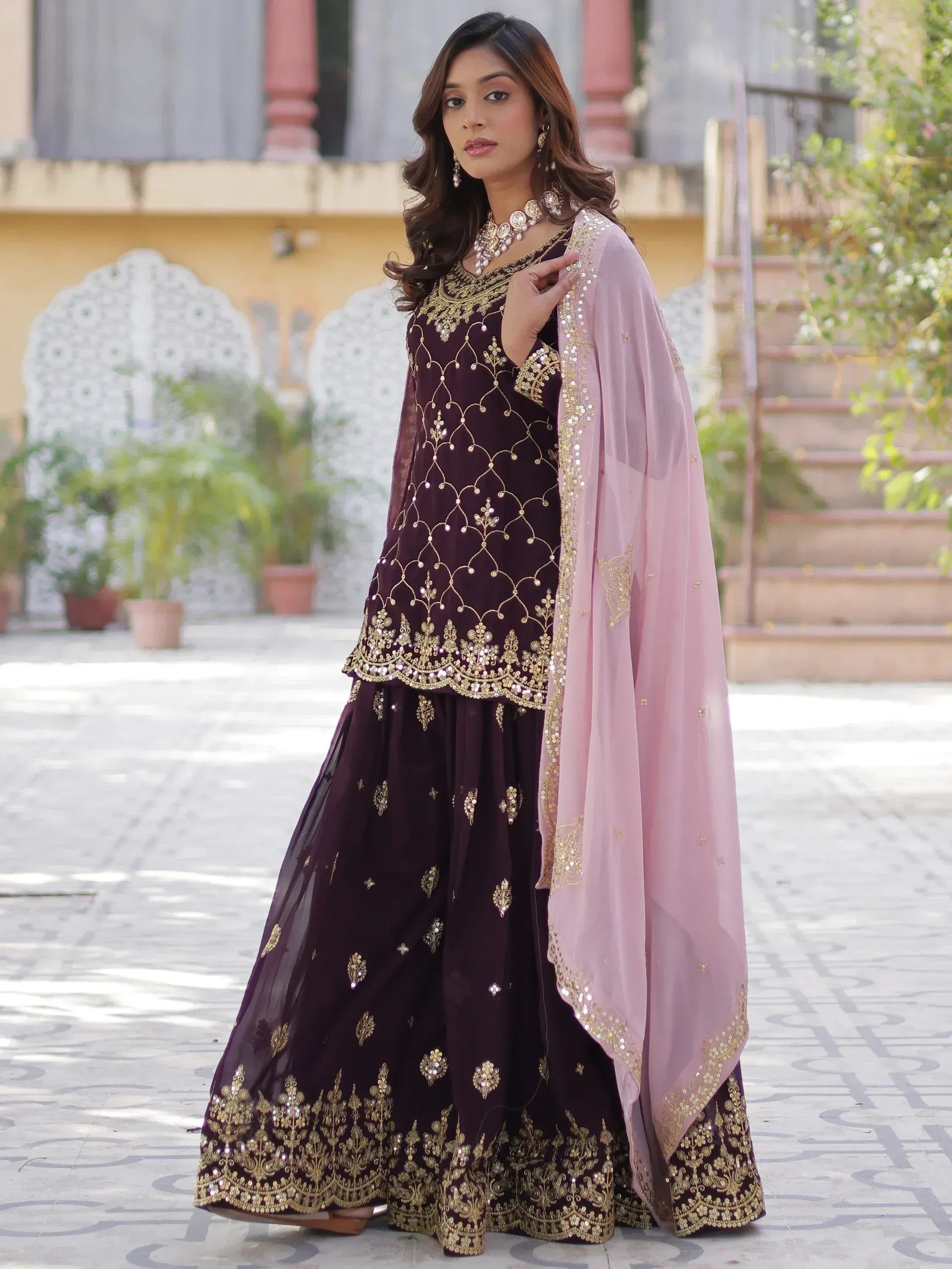 Elegant maroon Indian ethnic wear with gold embroidery and pink dupatta, perfect for festive occasions.