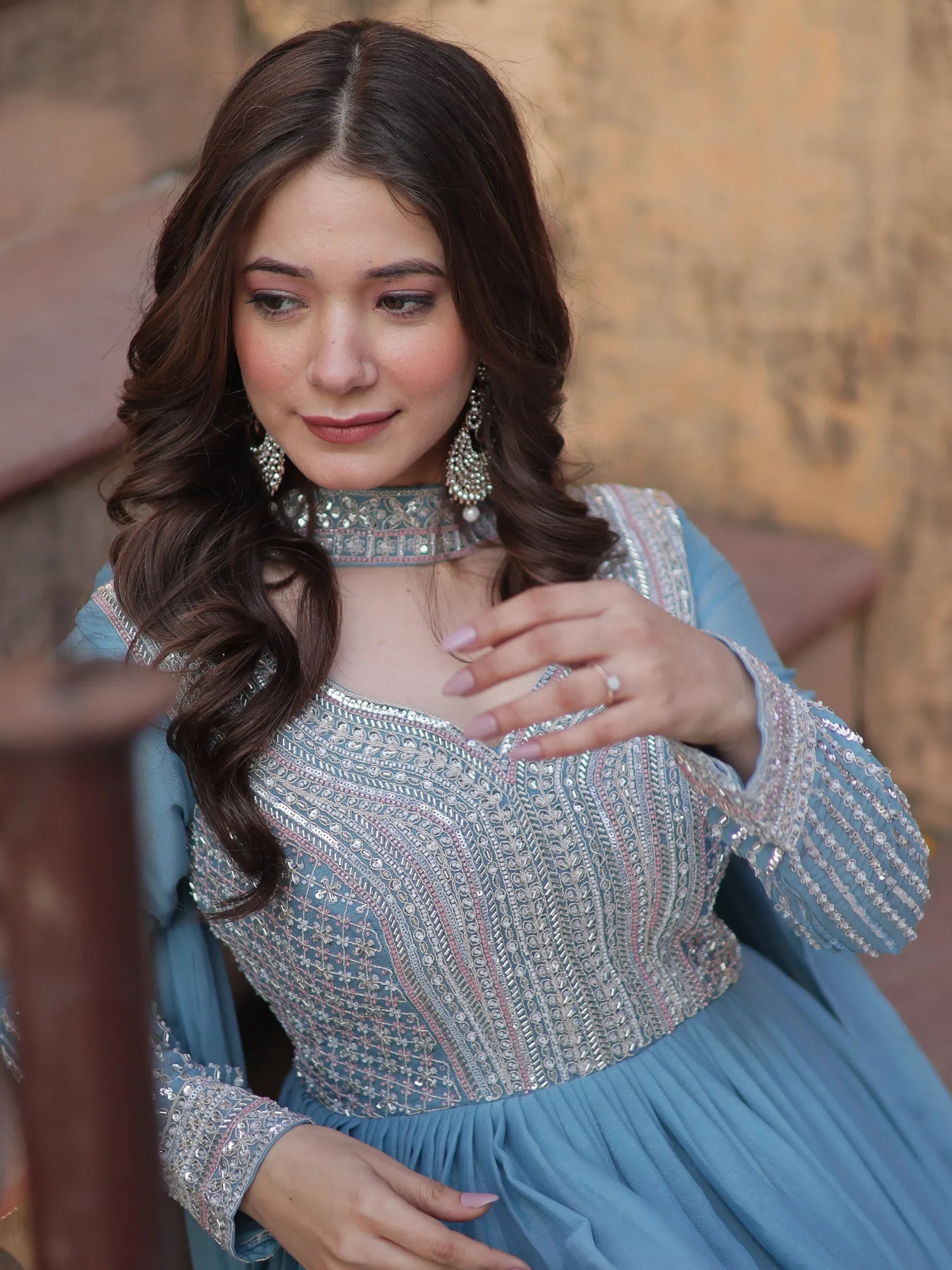 Woman in a sky blue ethnic gown with intricate silver embroidery and statement earrings