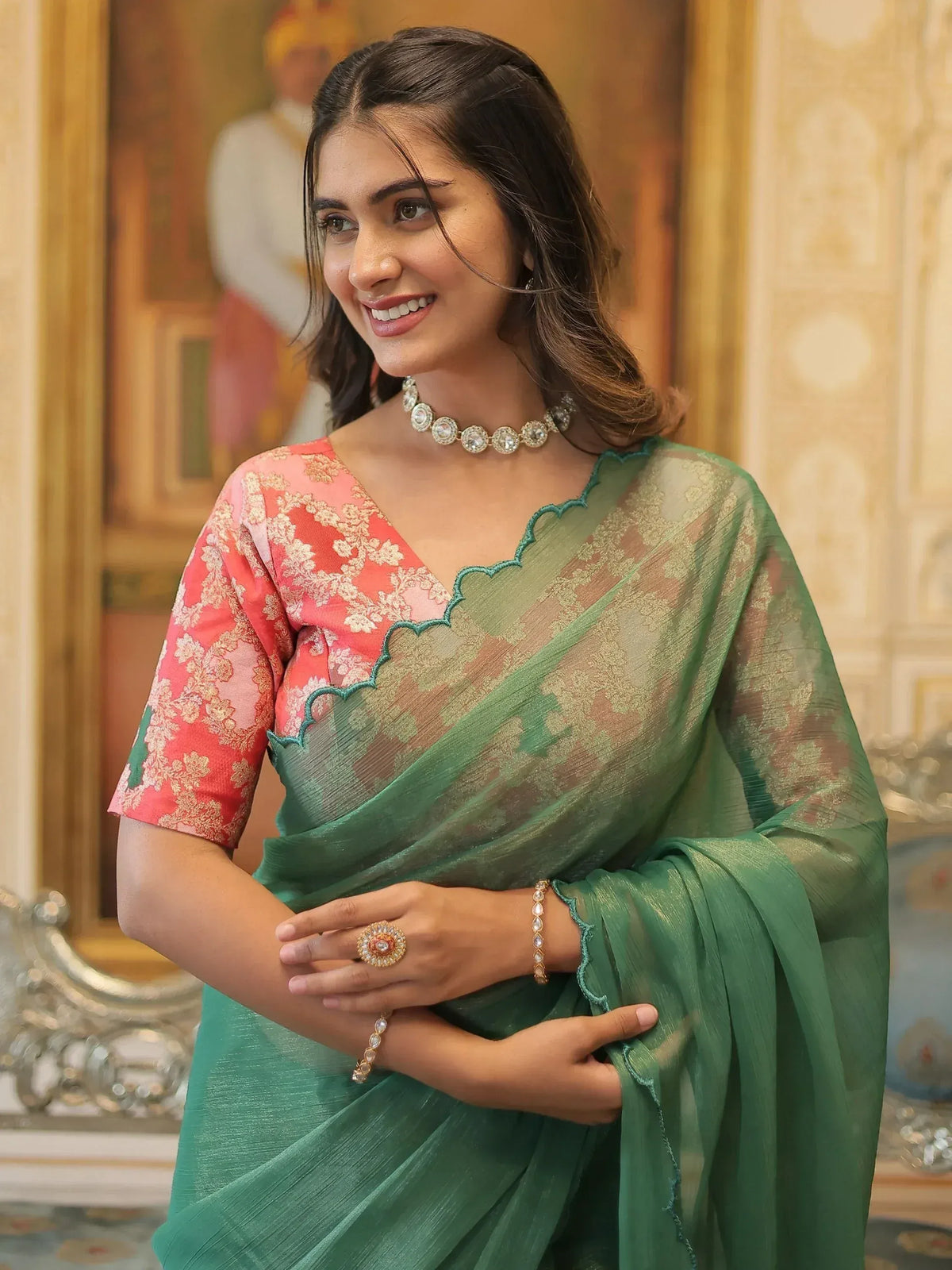 Woman in green sheer saree with pink floral blouse, ethnic jewelry, elegant Indian wear