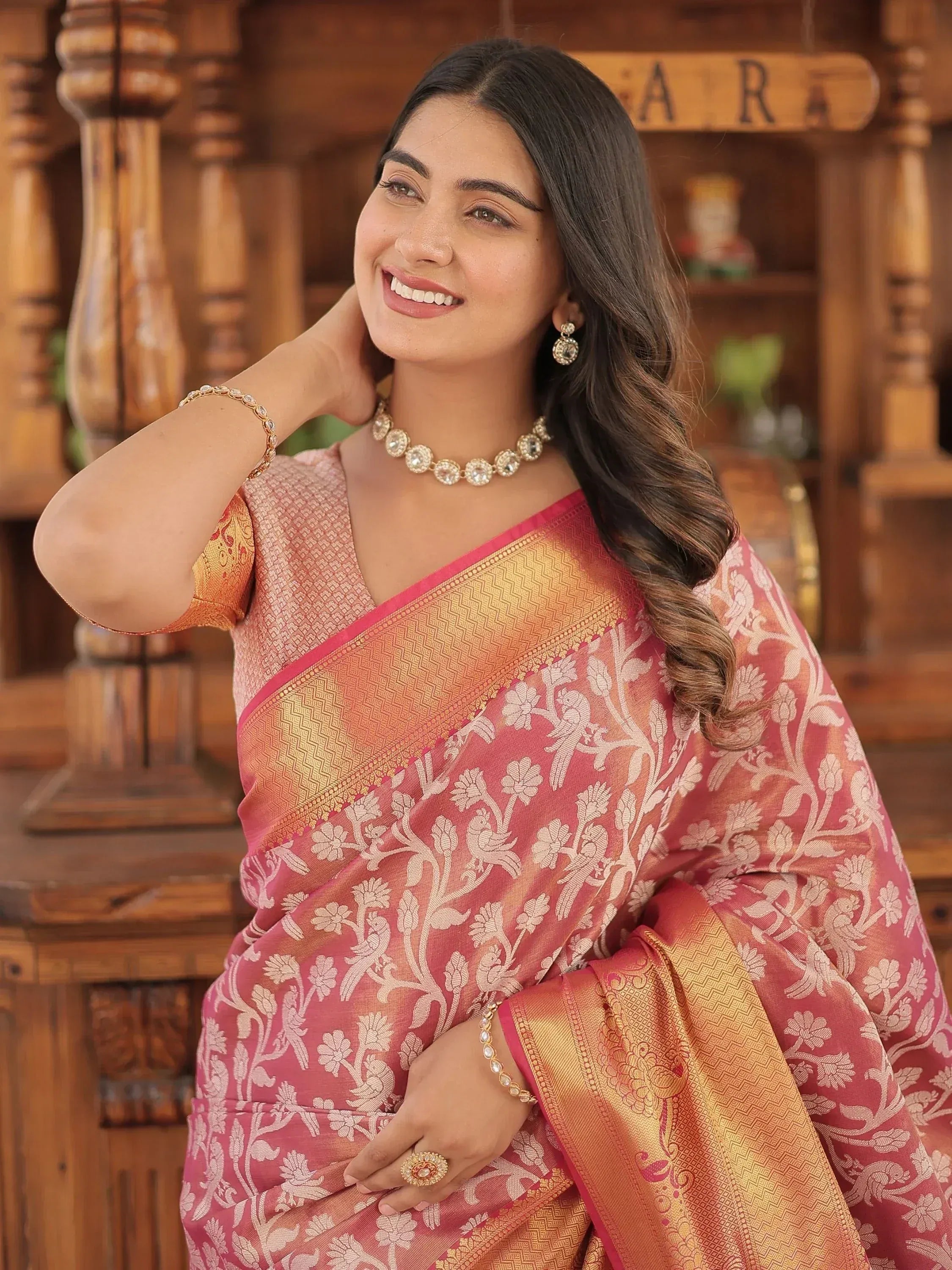 Woman in pink and gold floral saree with traditional jewelry, ethnic Indian wear
