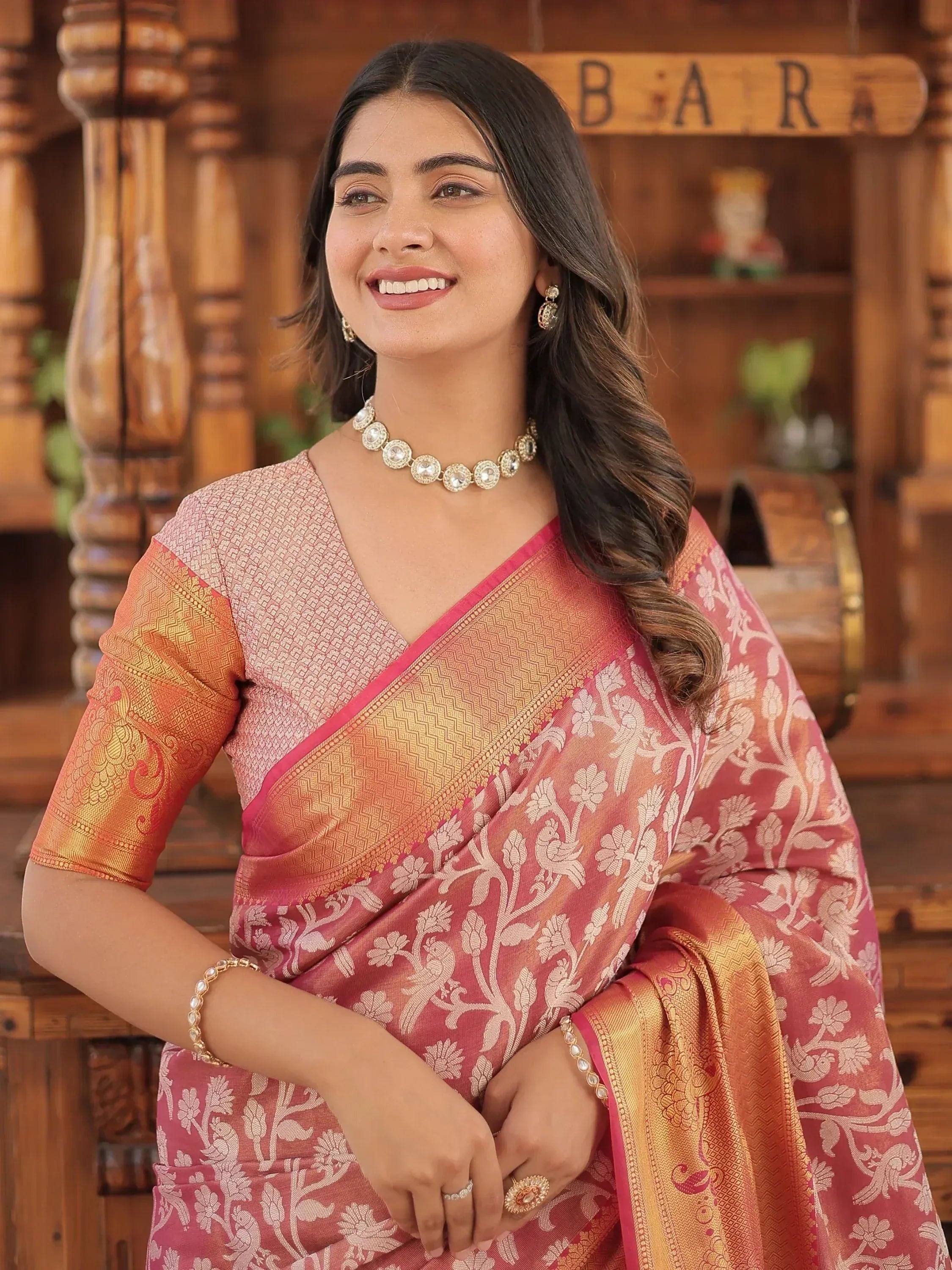 Woman in pink and gold floral saree with designer blouse, ethnic jewelry, traditional Indian wear
