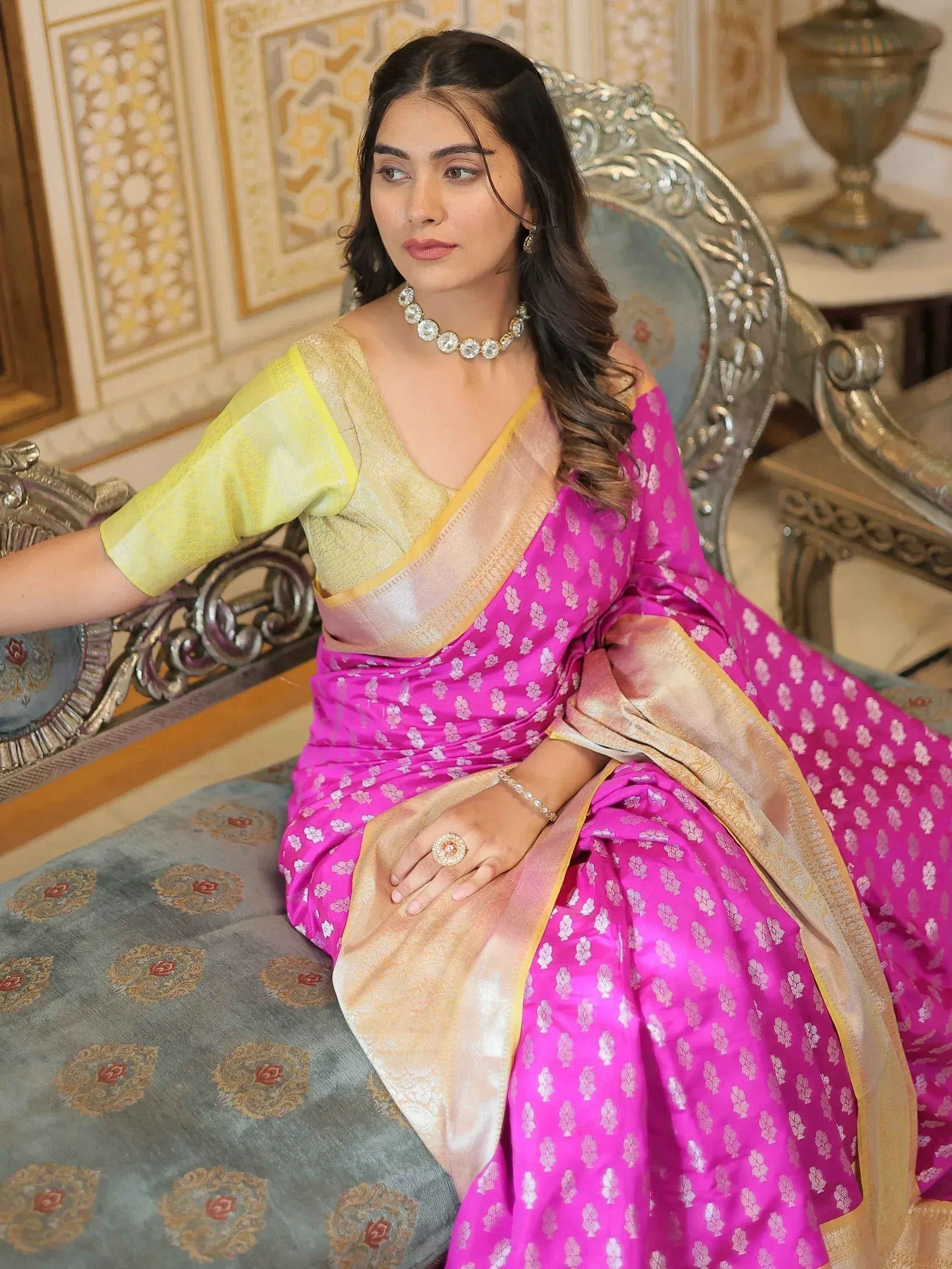 Woman in vibrant pink and gold ethnic saree with floral pattern, styled with designer jewelry for festive occasions.