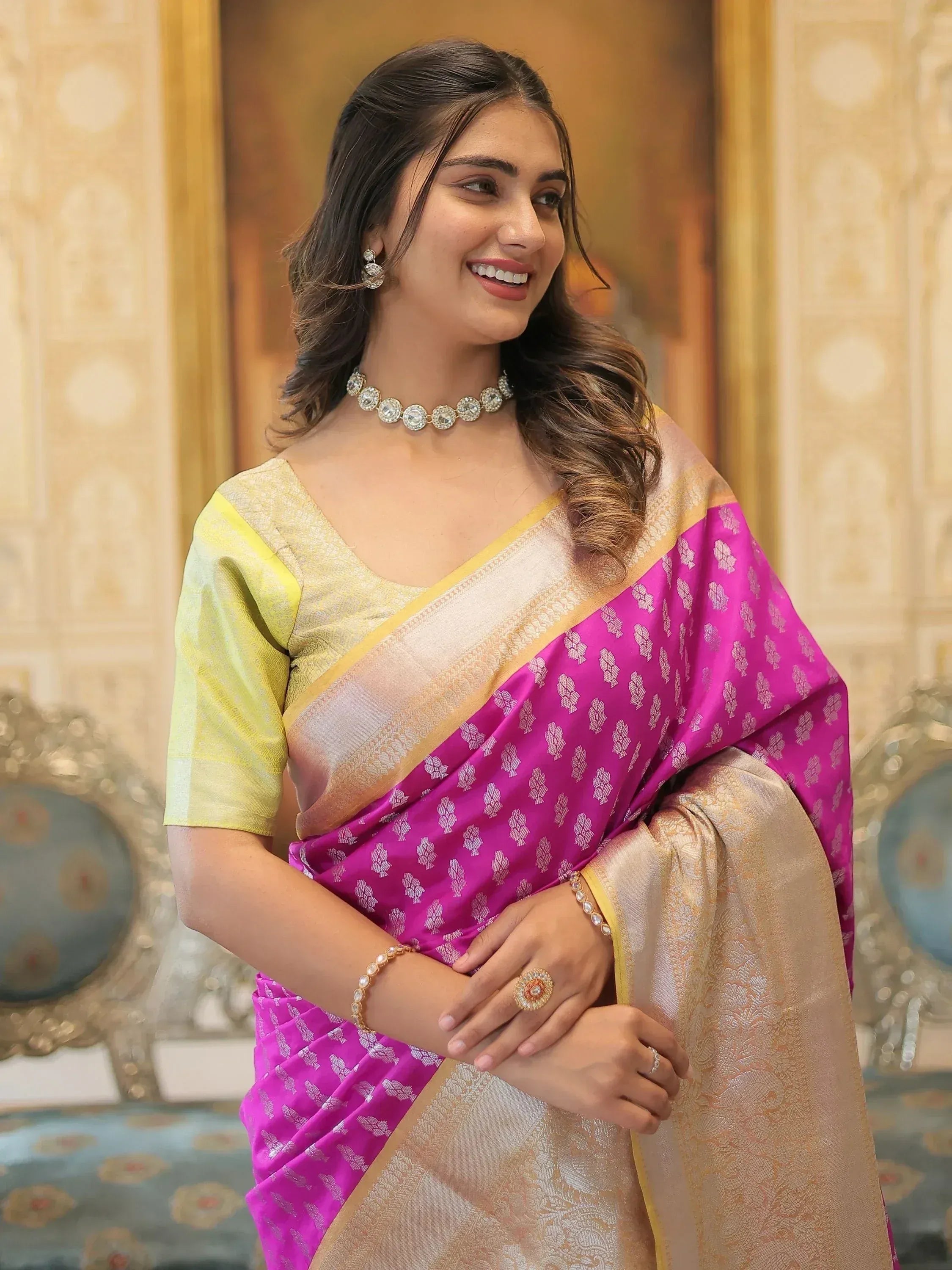 Woman in vibrant pink and gold ethnic saree with floral pattern, paired with designer jewelry for festive occasions