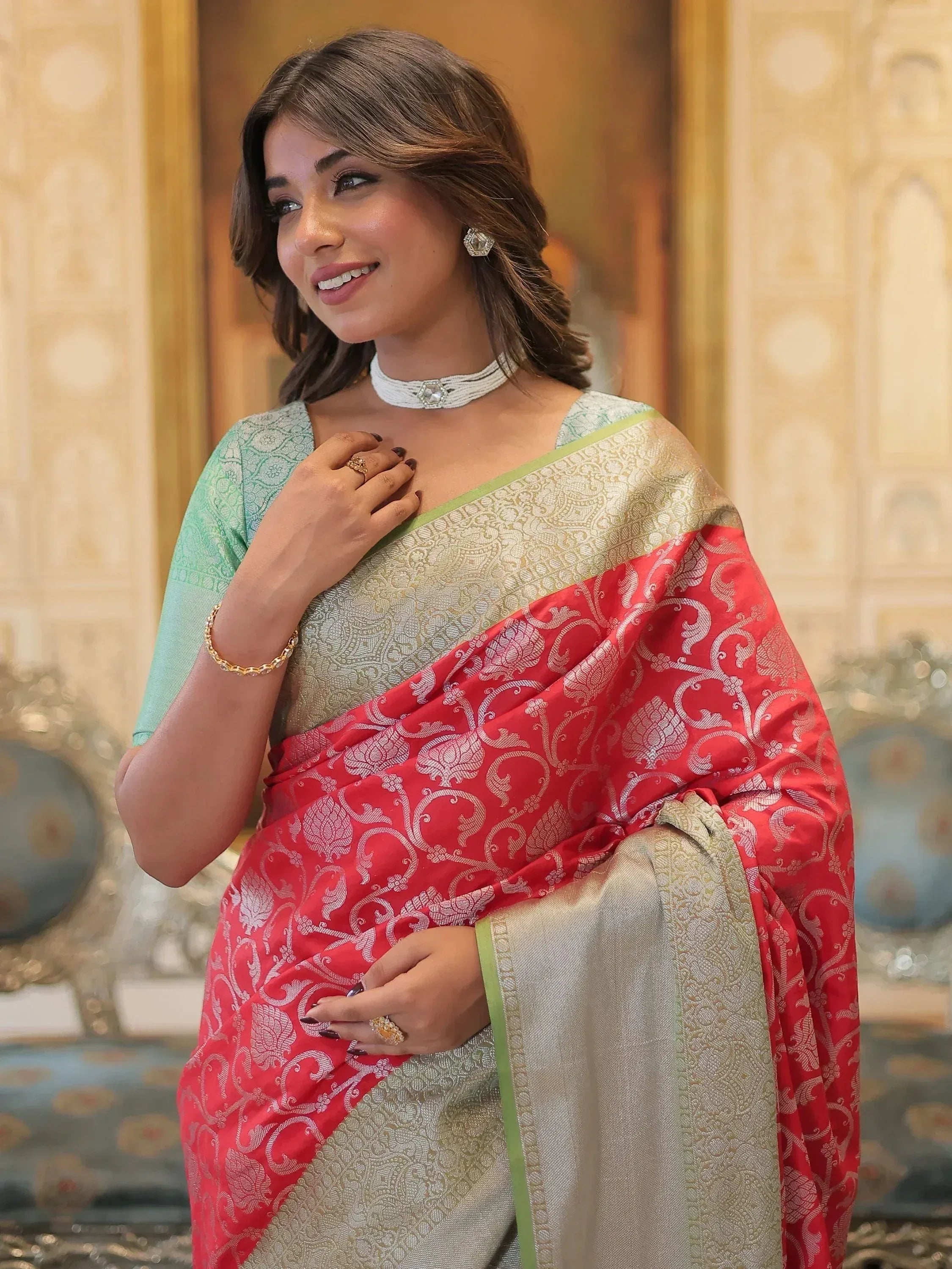 Woman in elegant red and gold designer saree with intricate patterns, paired with mint blouse for Indian ethnic wear