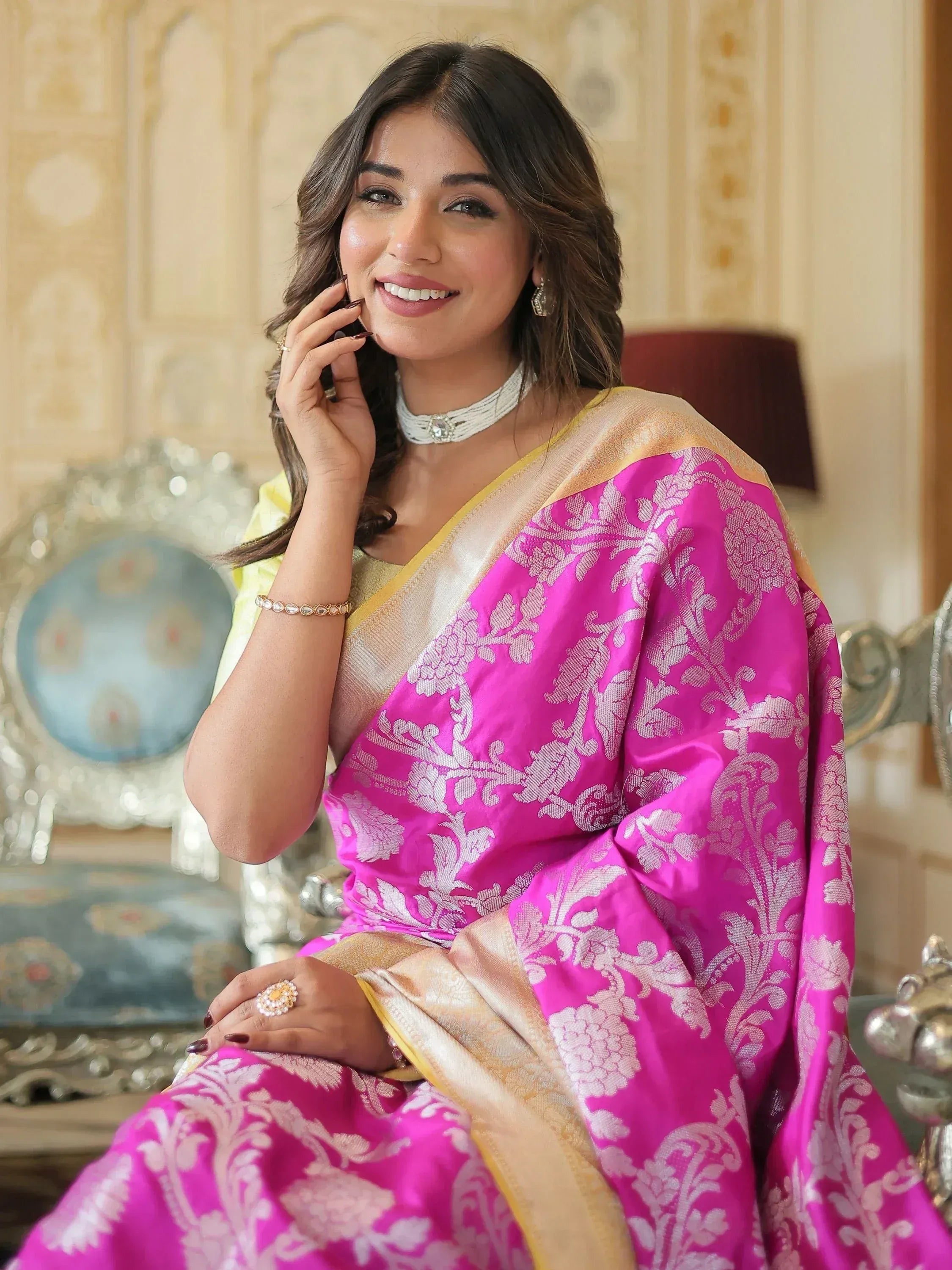 Woman in vibrant pink floral saree with gold border, elegant ethnic wear for festive occasions