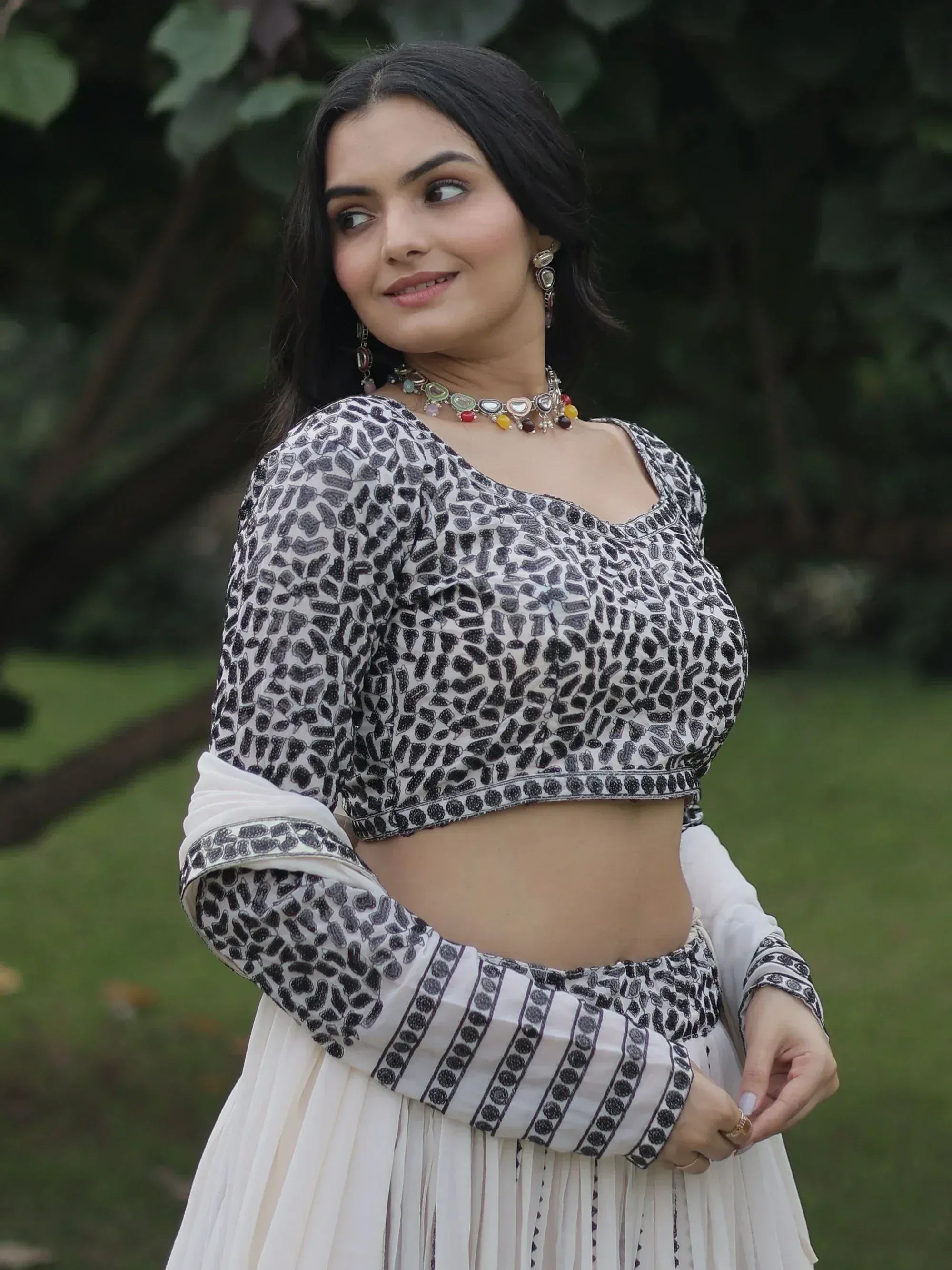 Woman in black and white printed ethnic crop top with pleated skirt, styled with traditional jewelry for Indian wear