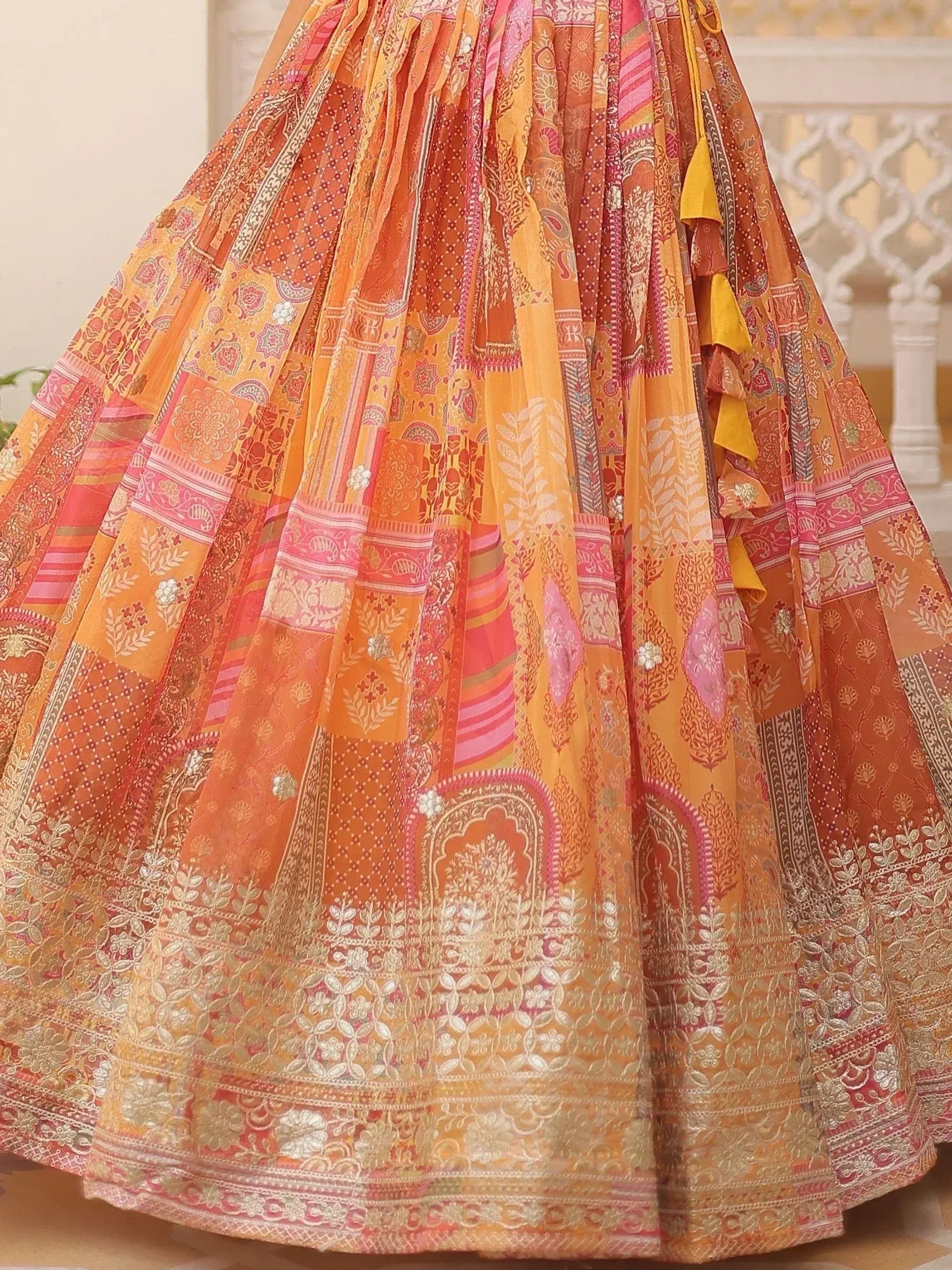 Vibrant orange and pink patchwork lehenga with intricate floral and paisley prints, perfect for Indian ethnic wear.