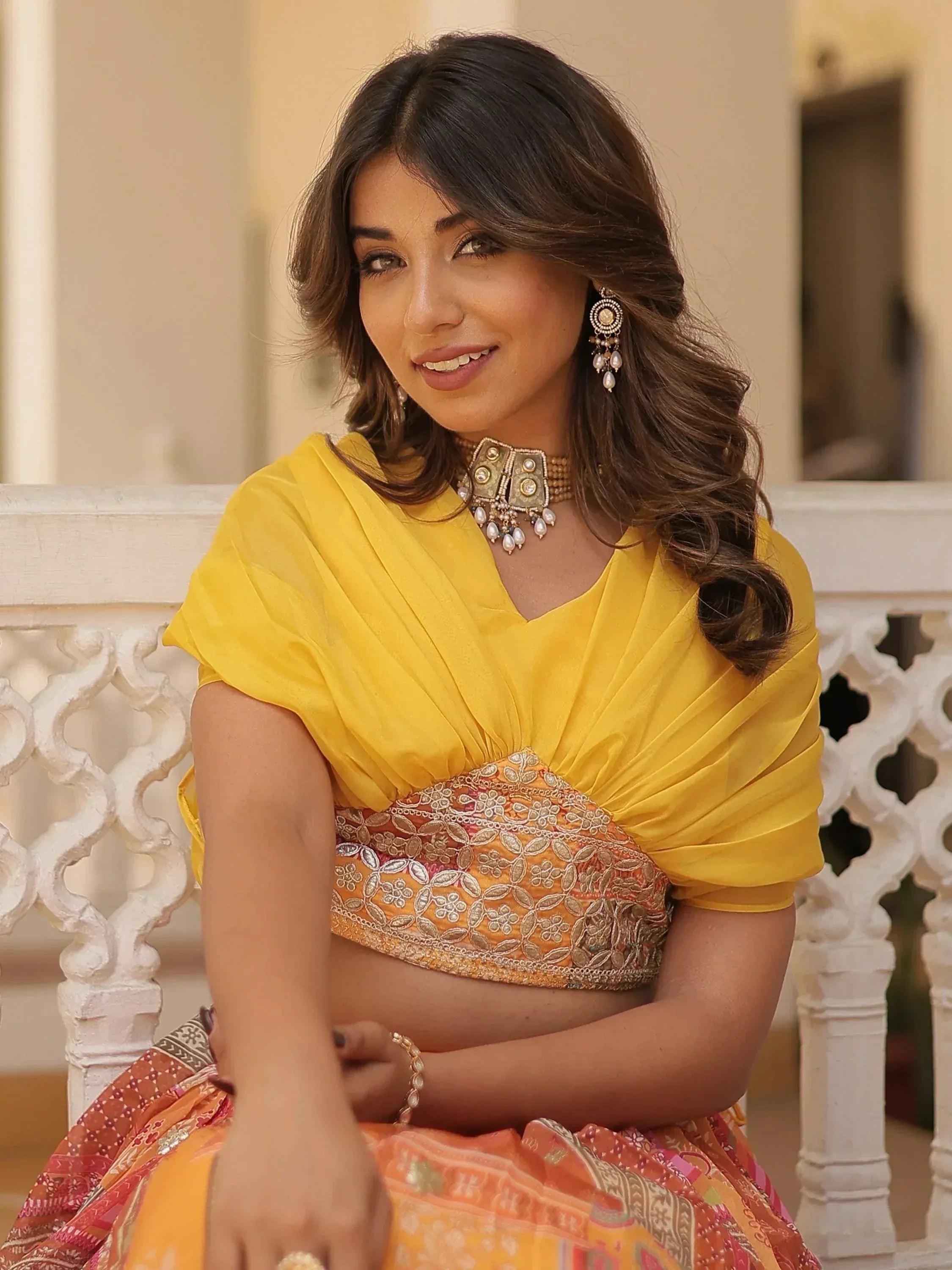 Yellow embroidered lehenga choli with floral patterns, paired with statement jewelry for festive occasions.