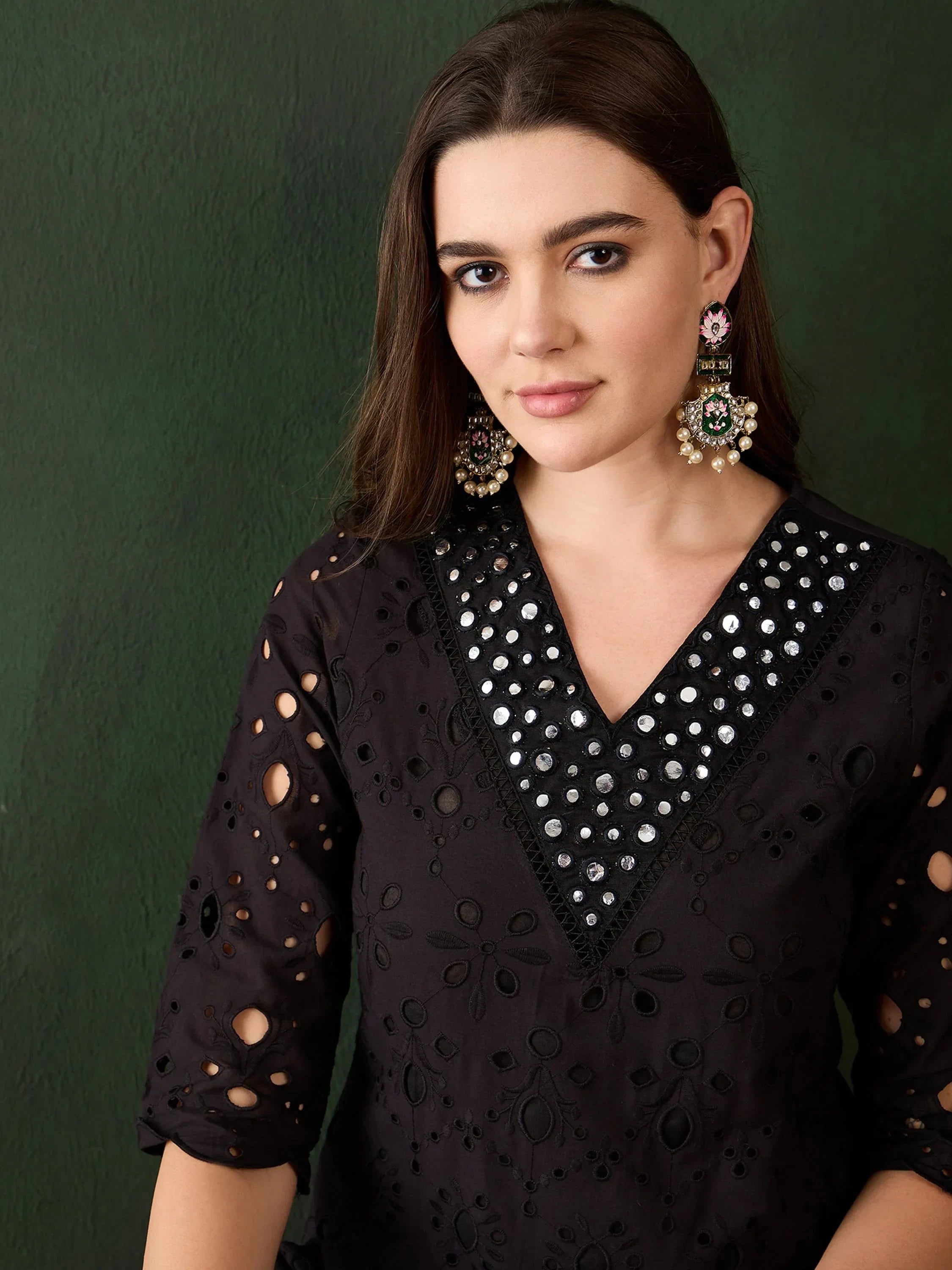 Woman in black embroidered kurti with mirror work, wearing statement ethnic earrings