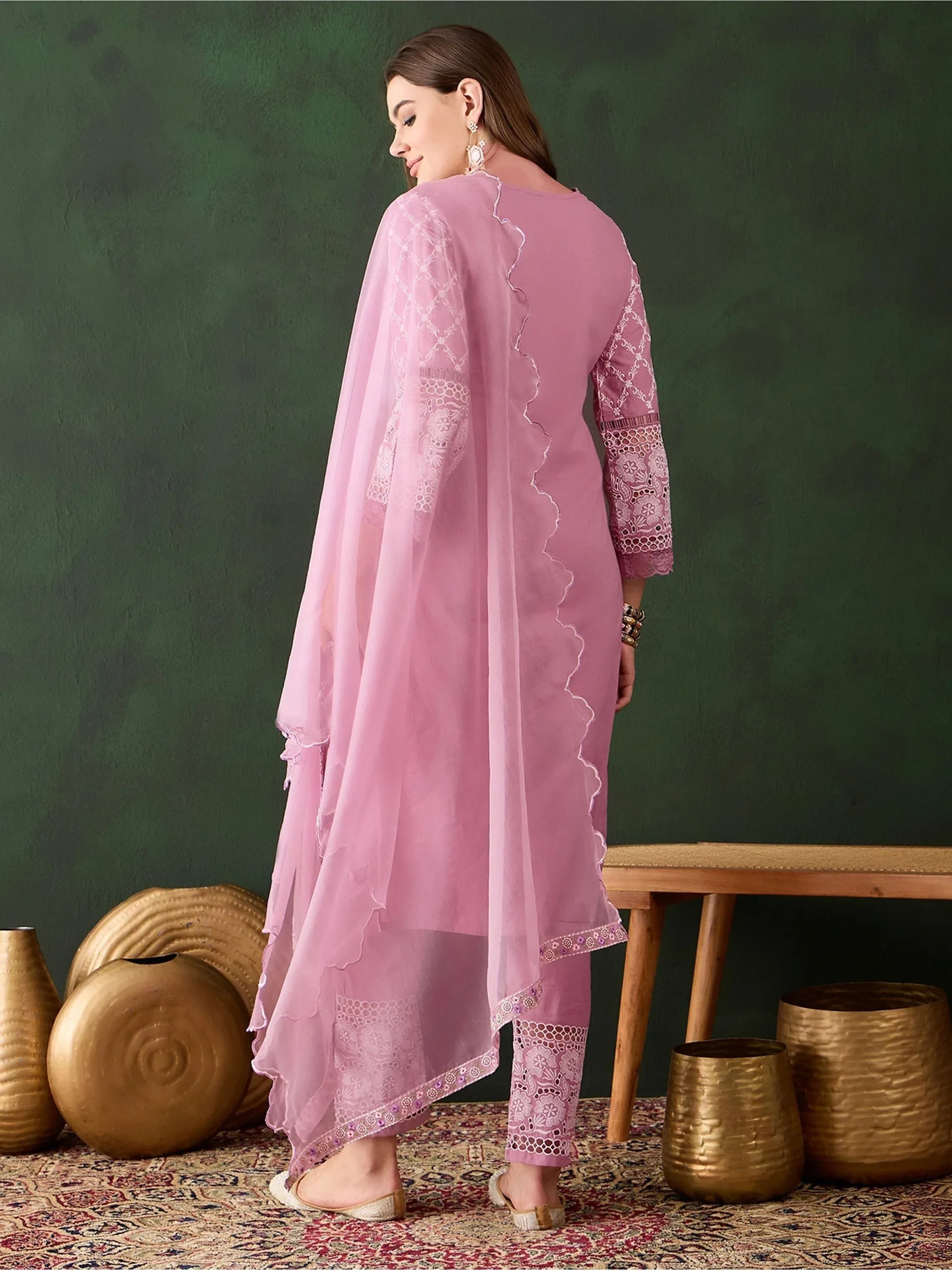 Woman wearing pink embroidered salwar kameez with dupatta, standing on patterned rug
