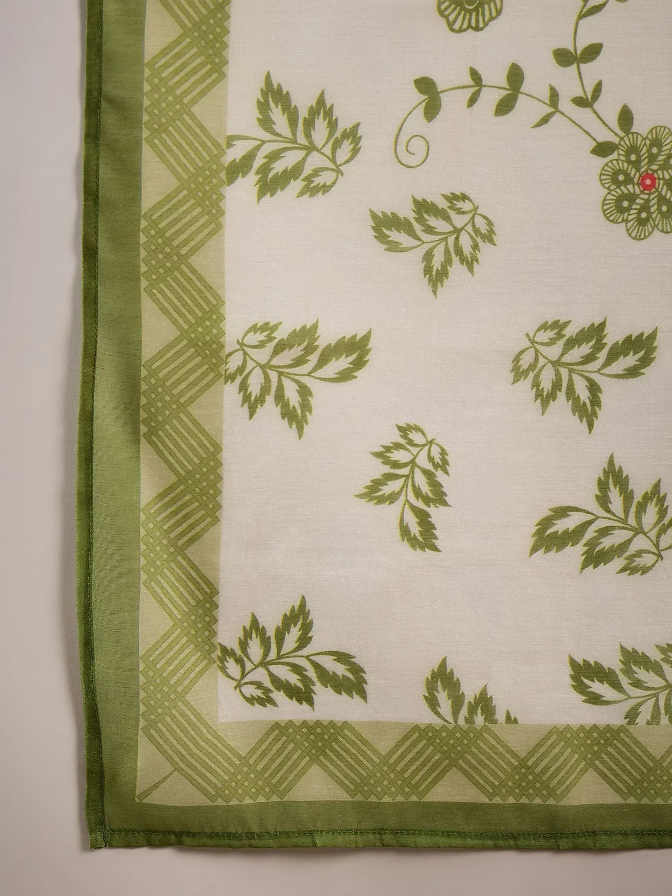 Green leaf and floral print fabric with geometric border, ideal for ethnic wear like salwar kameez or sarees.