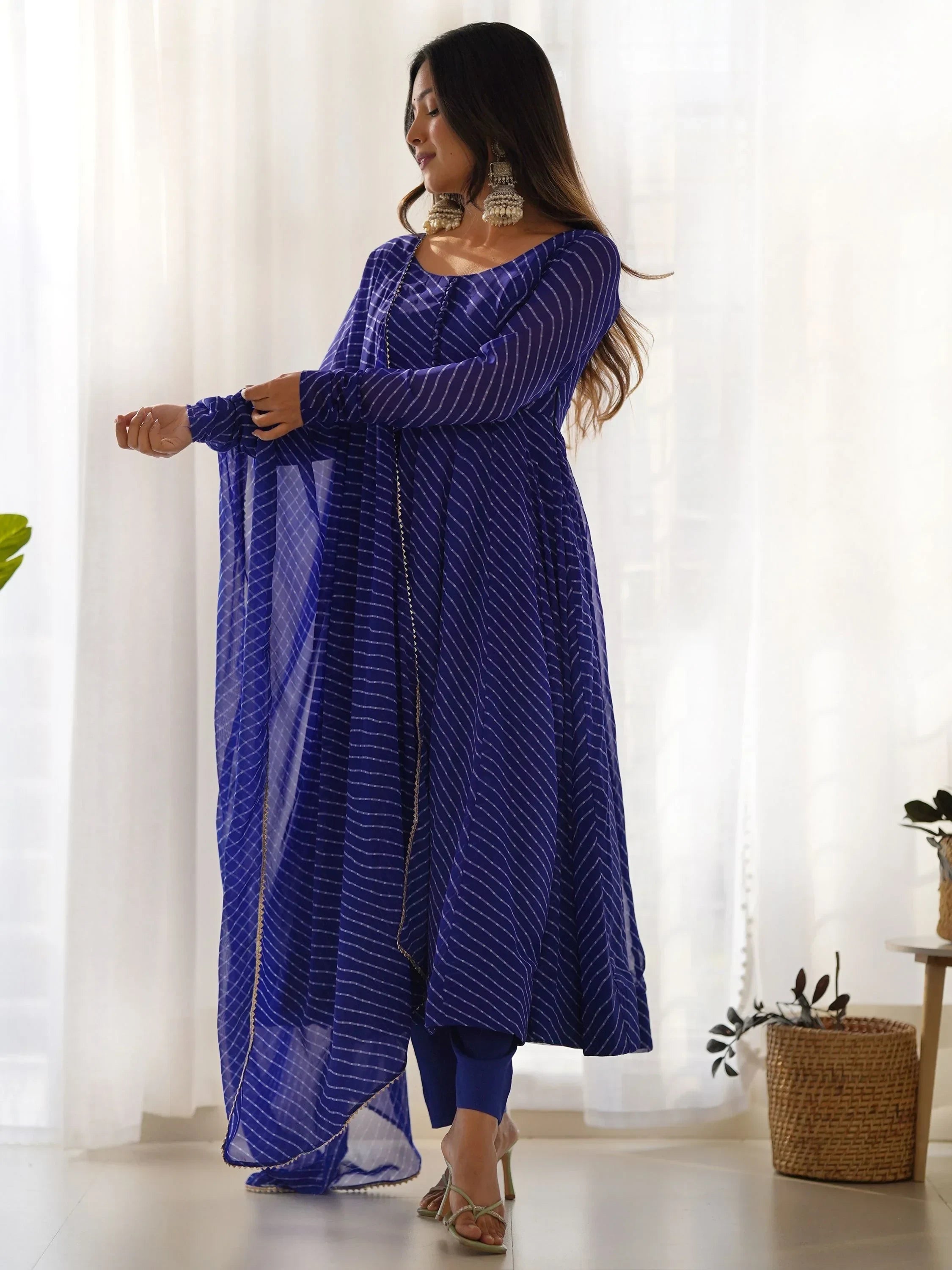 Woman wearing a blue striped Indian Anarkali suit with dupatta, standing indoors