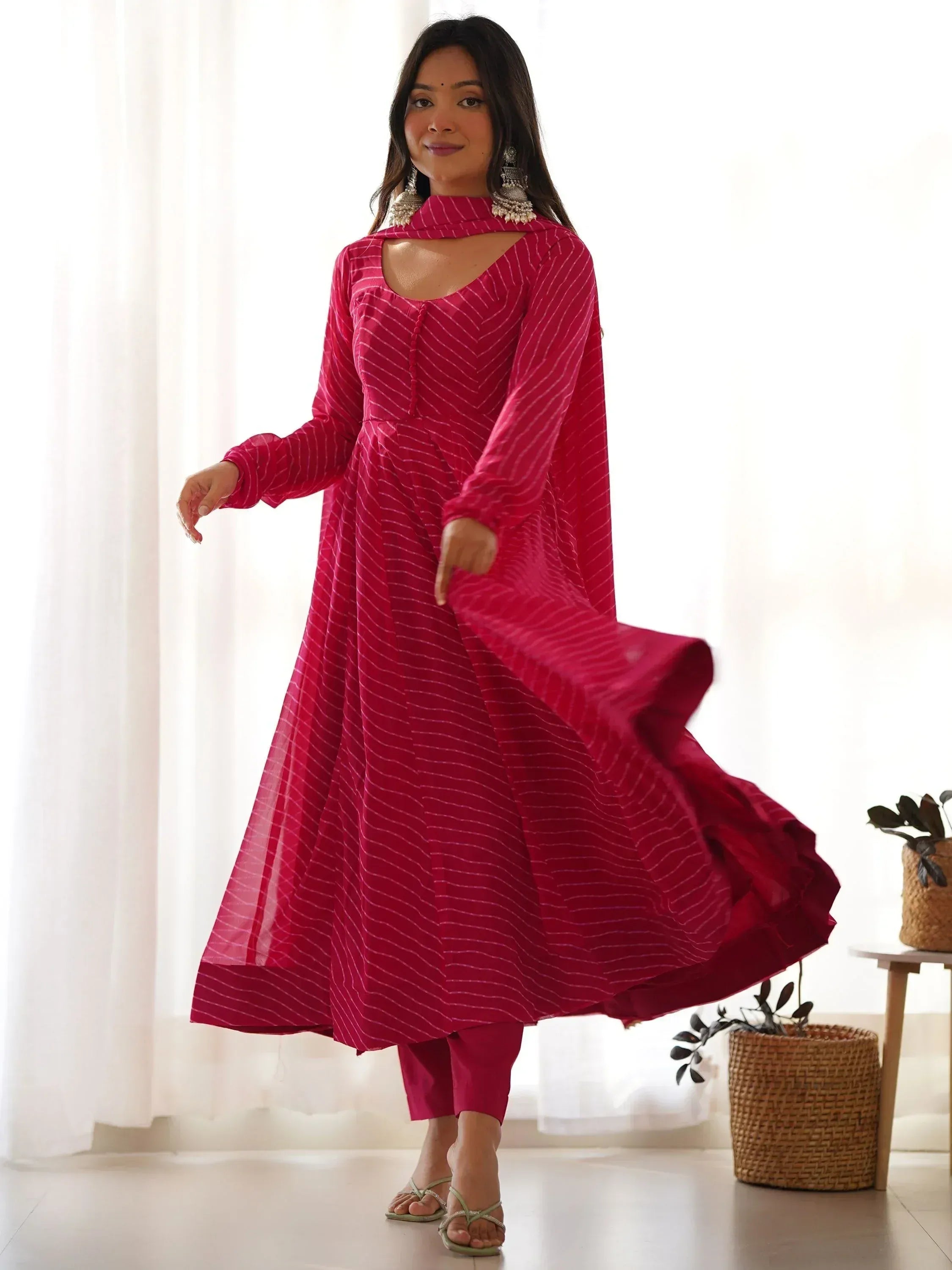 Woman in pink striped ethnic anarkali gown with cutout neckline, perfect for Indian occasions