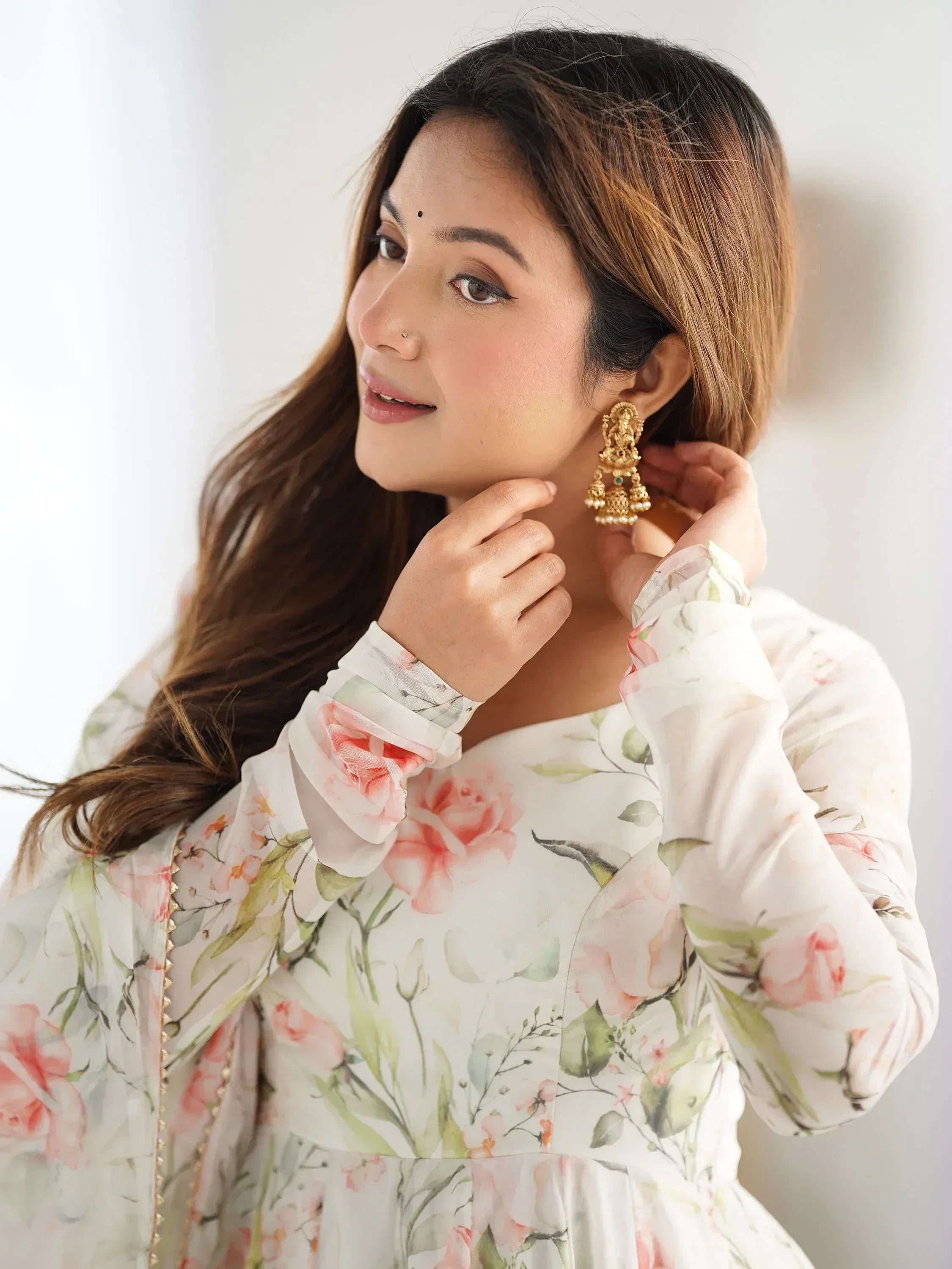 Woman in floral printed ethnic gown with gold jhumka earrings, showcasing Indian fashion