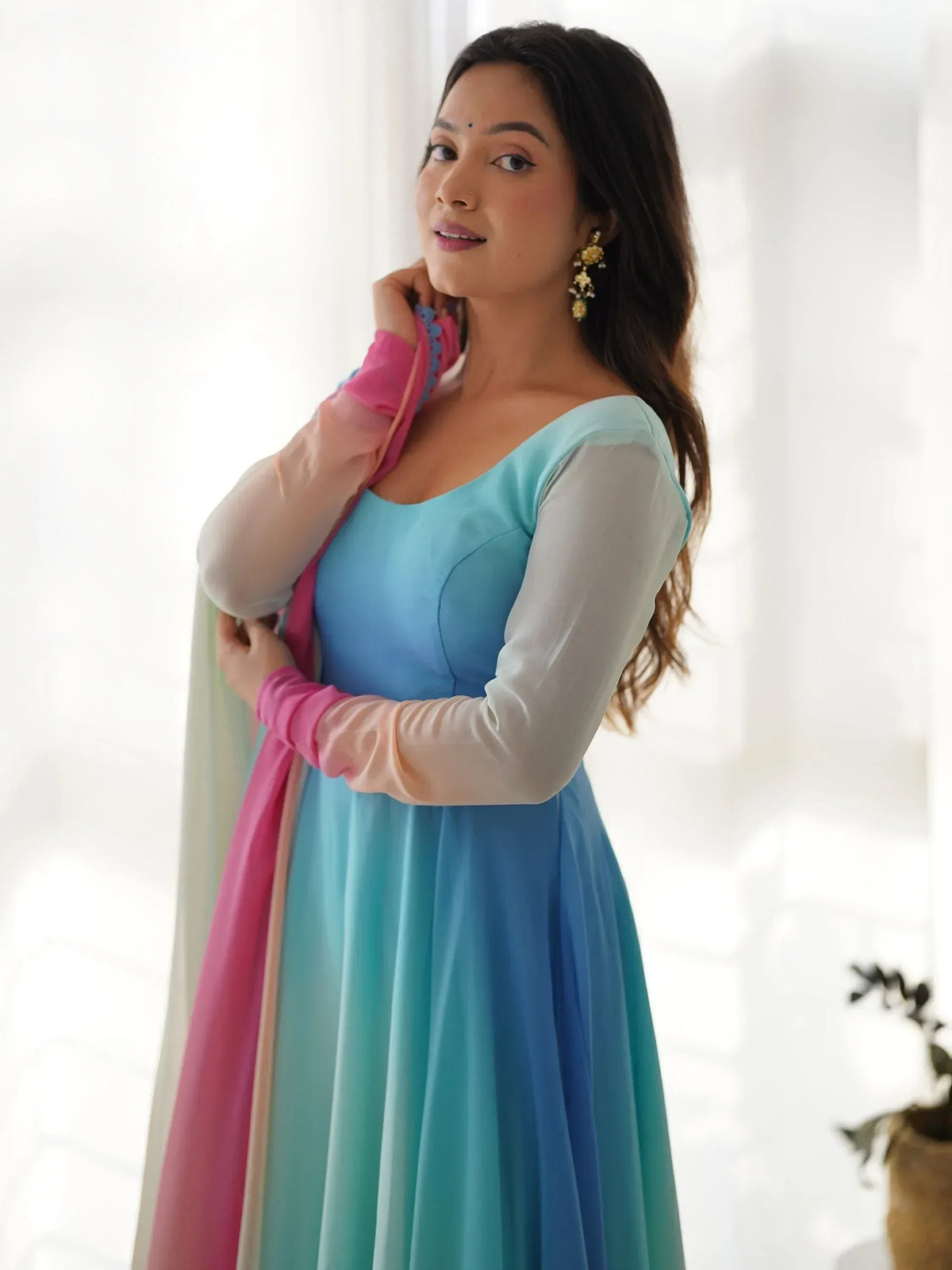Woman in blue ombre ethnic gown with sheer sleeves and pink dupatta, styled for Indian occasions