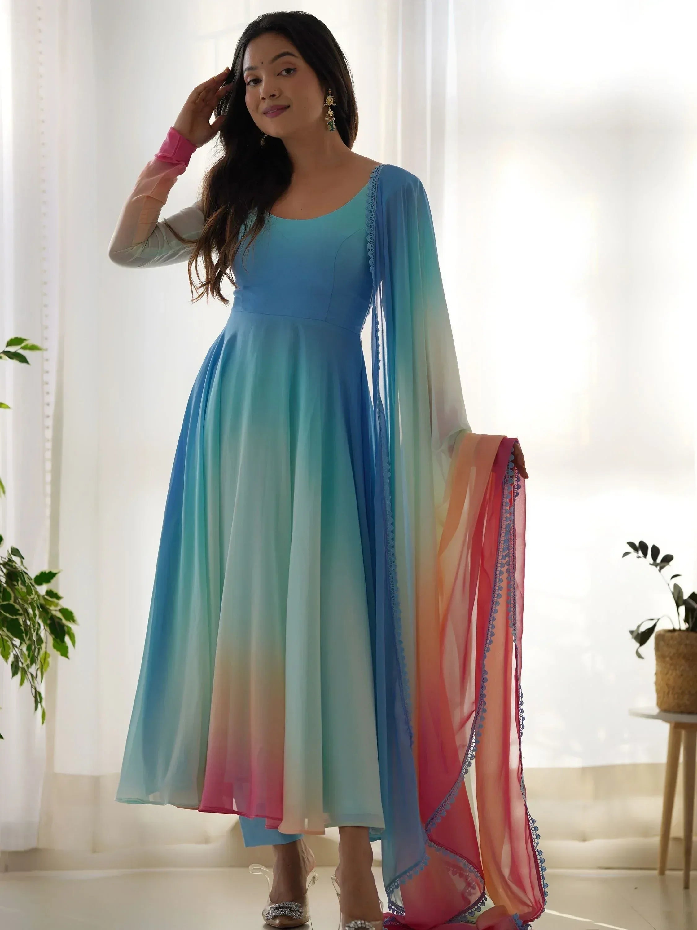 Woman in ombre blue to pink Indian ethnic gown with matching dupatta, perfect for festive occasions.