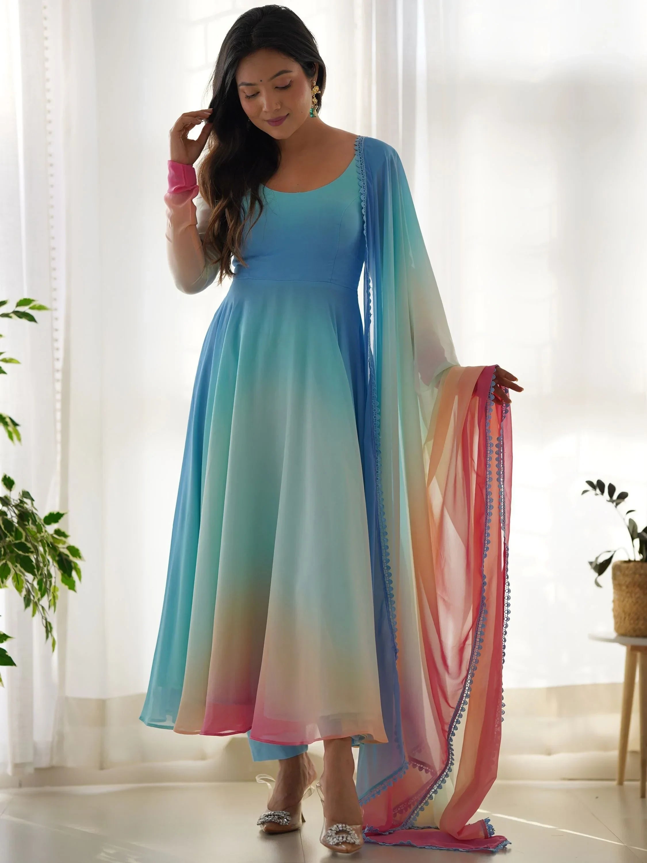 Woman wearing pastel multicolor Anarkali suit with matching dupatta, standing indoors