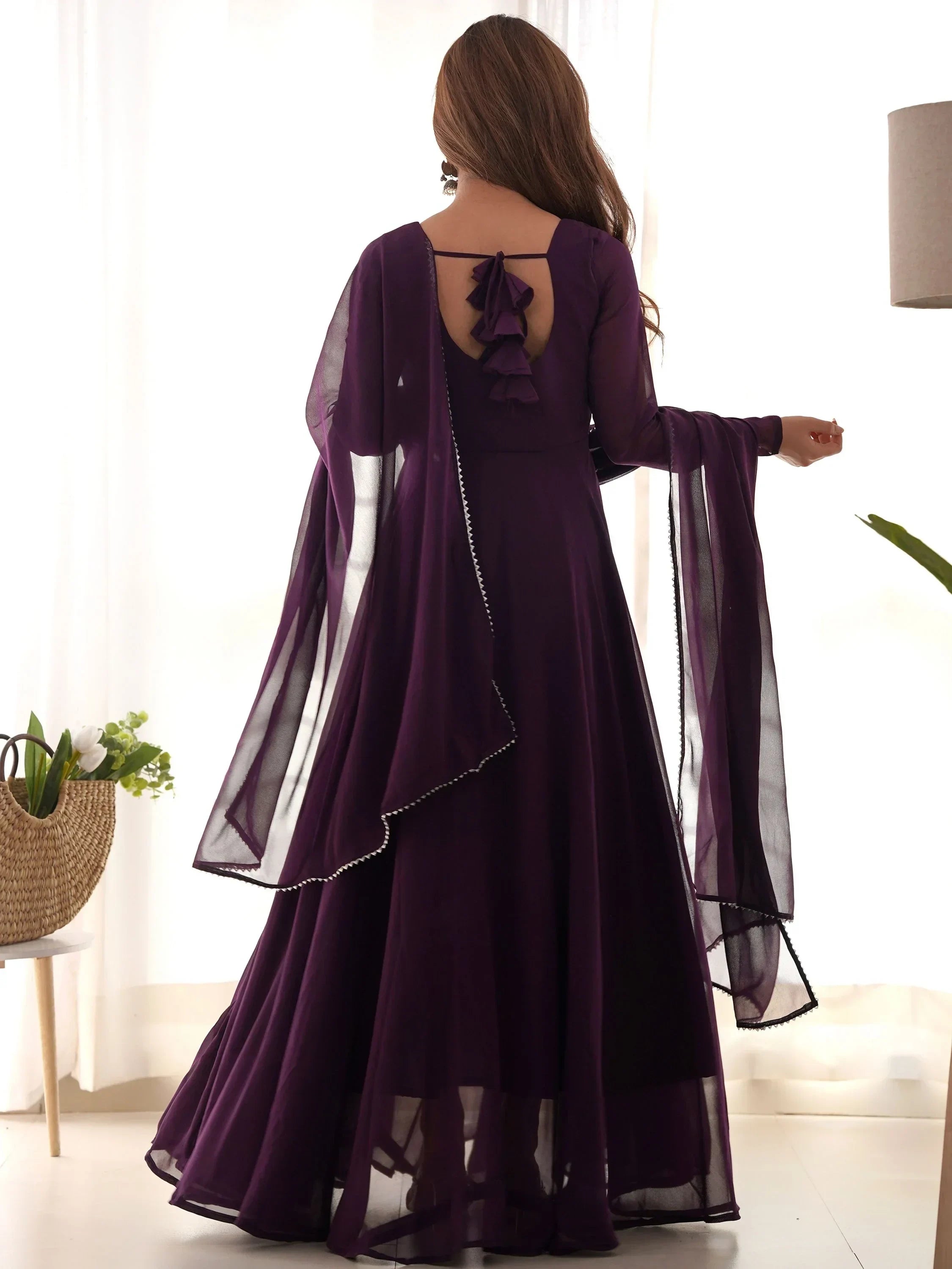 Back view of woman in a deep purple flared ethnic gown with dupatta and ruffle detail