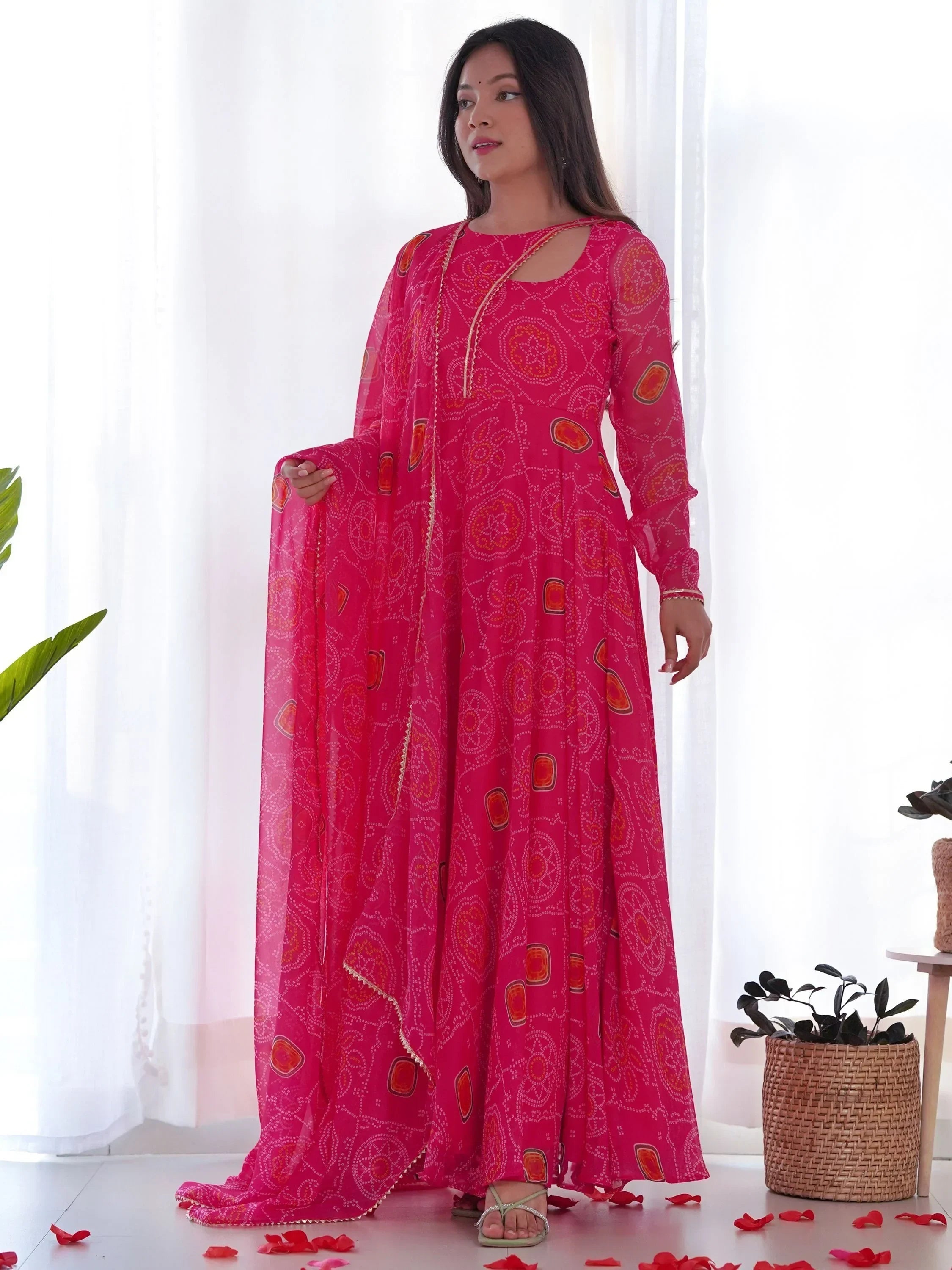 Woman in a vibrant pink ethnic gown with traditional bandhani print and dupatta
