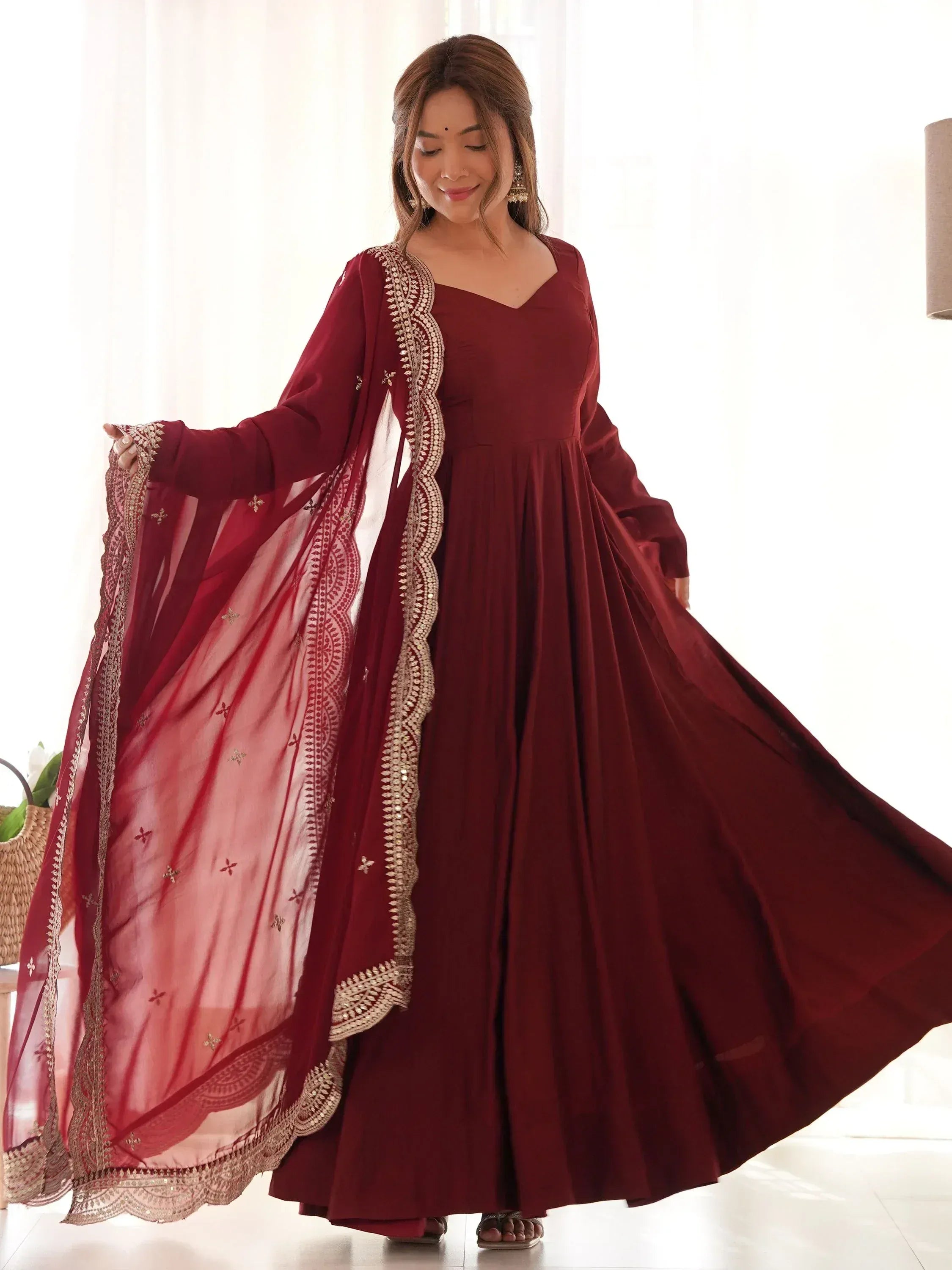 Maroon ethnic gown with gold embroidery and sheer dupatta, perfect for Indian celebrations
