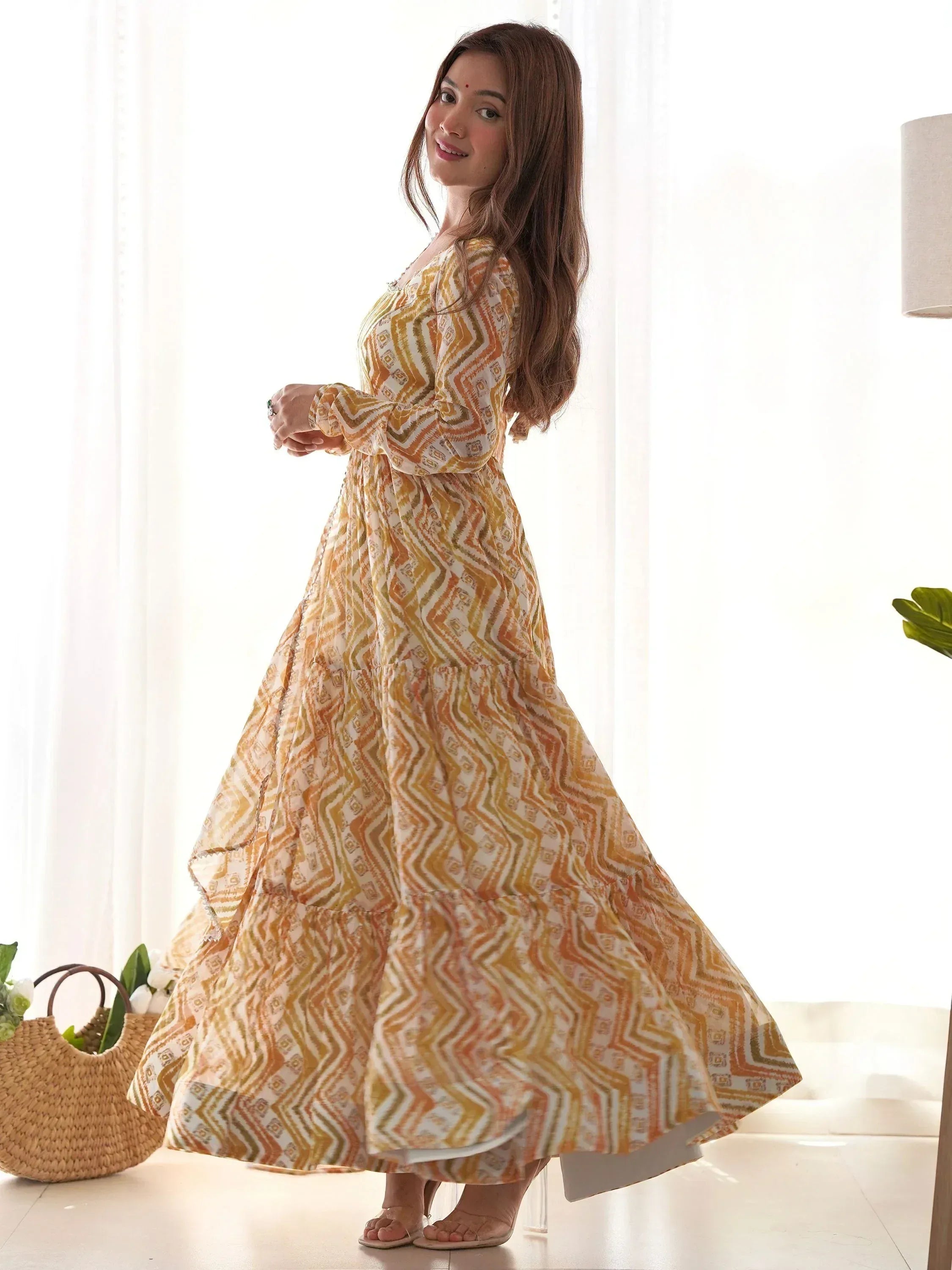 Woman in yellow geometric print ethnic gown with tiered skirt, long sleeves, perfect for Indian occasions