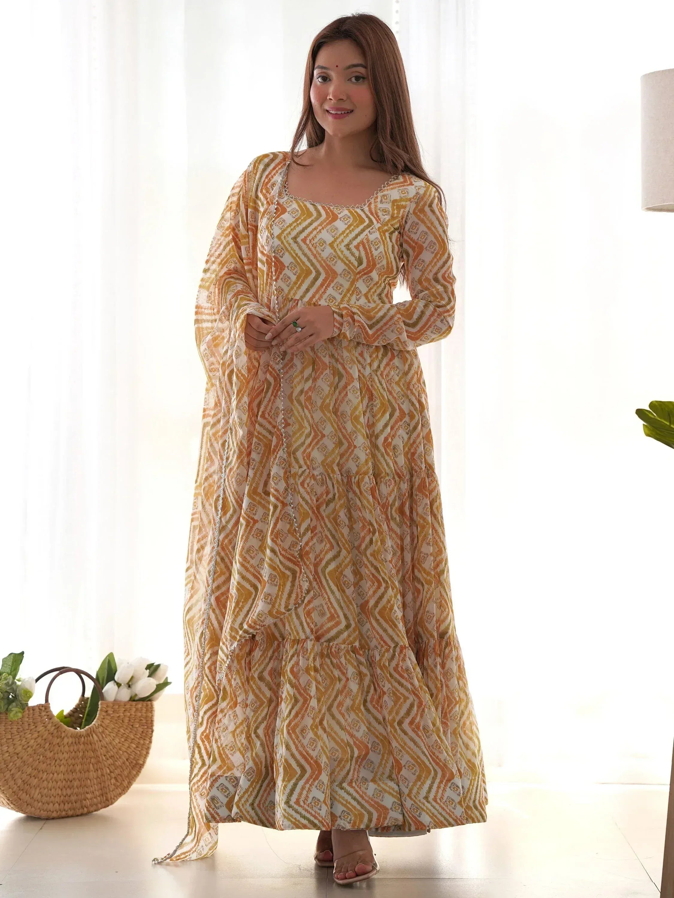 Woman in orange and white geometric print ethnic gown with tiered skirt and bell sleeves