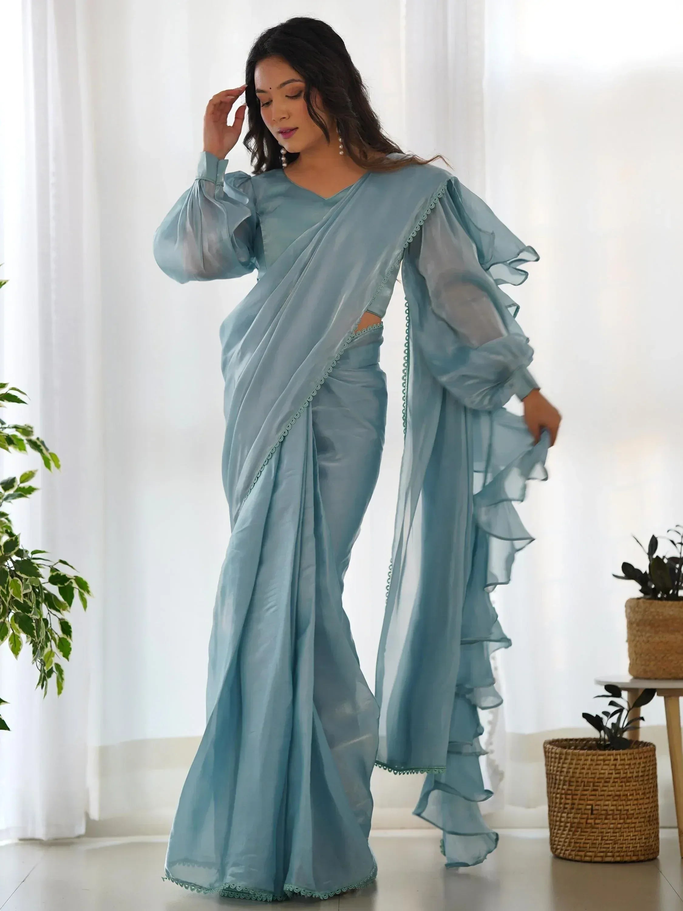 Light blue saree with ruffled sleeves and scalloped edges, styled for ethnic wear occasions.