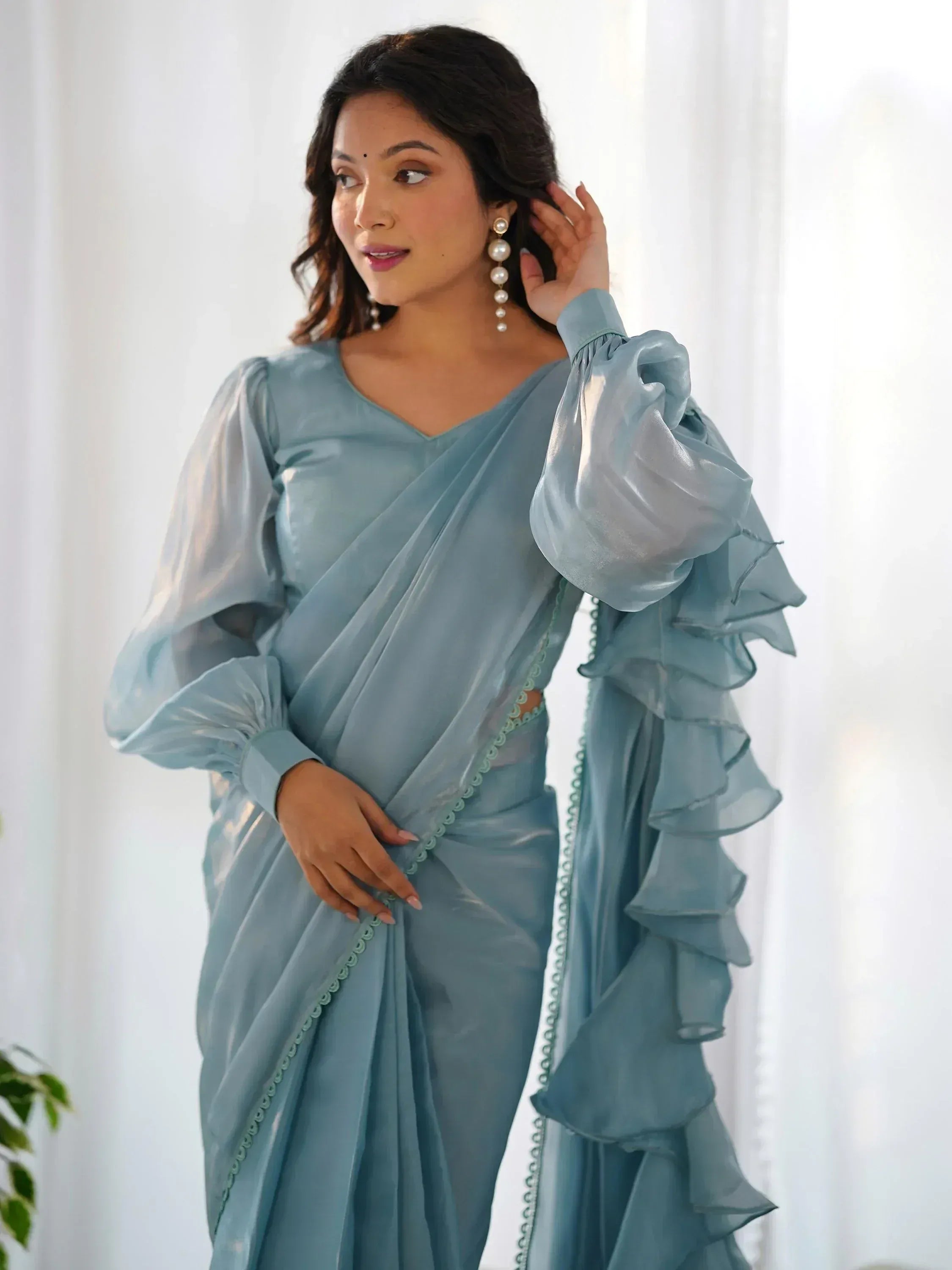 Woman in elegant light blue saree with ruffled sleeves and pearl earrings, Indian ethnic wear