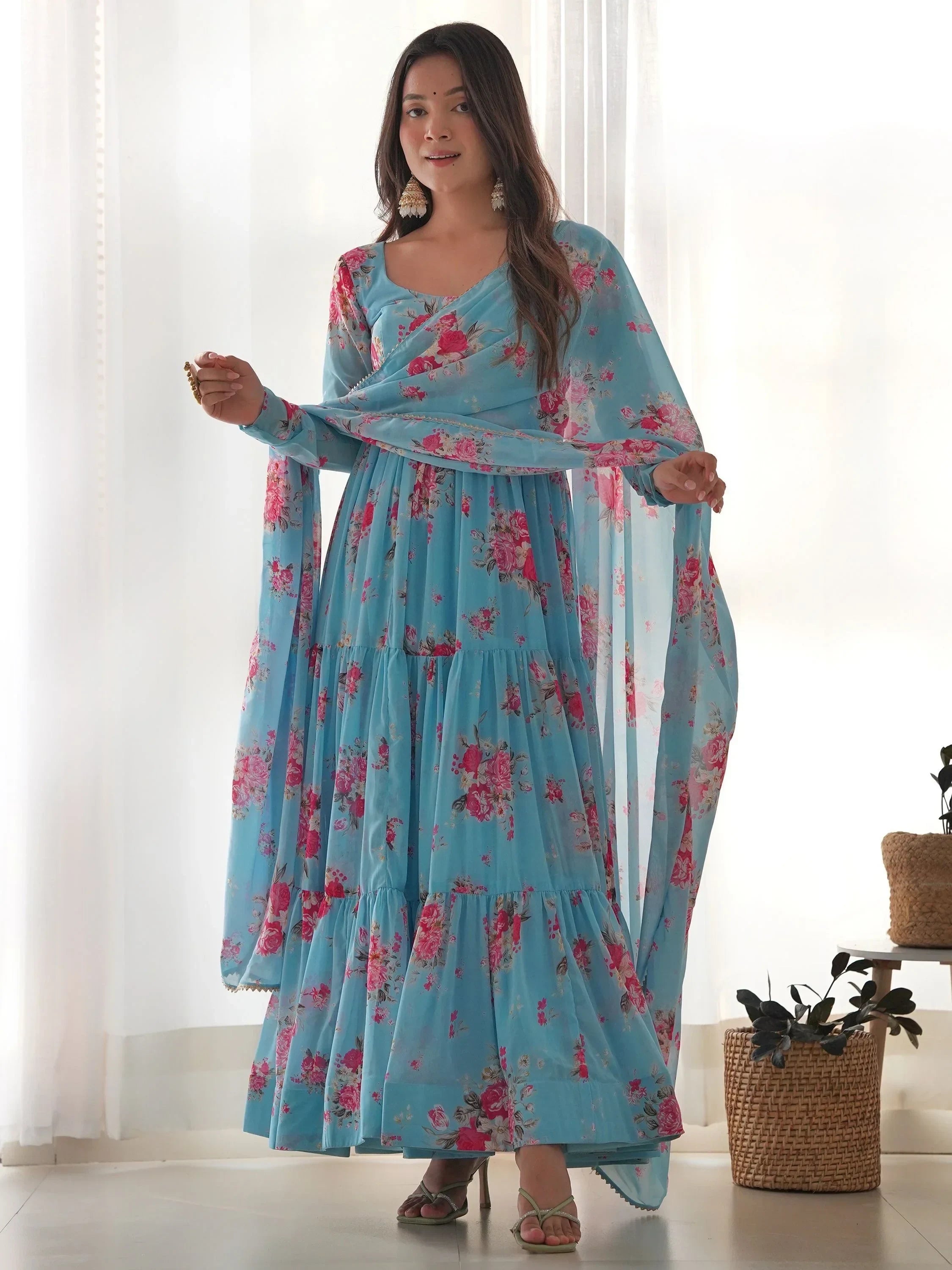 Woman in light blue floral Indian ethnic gown with dupatta, standing indoors