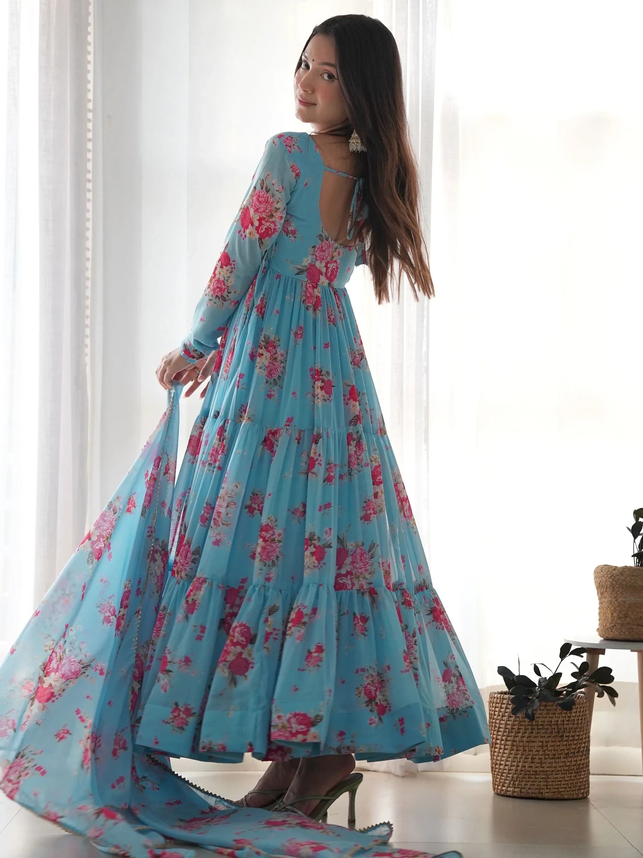 Woman in a blue floral ethnic gown with dupatta, long sleeves, standing indoors