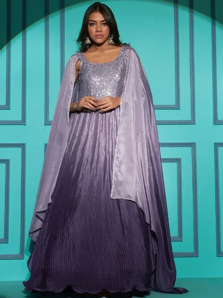 Woman wearing a lavender sequin ethnic gown with cape sleeves, stylish Indian party wear.