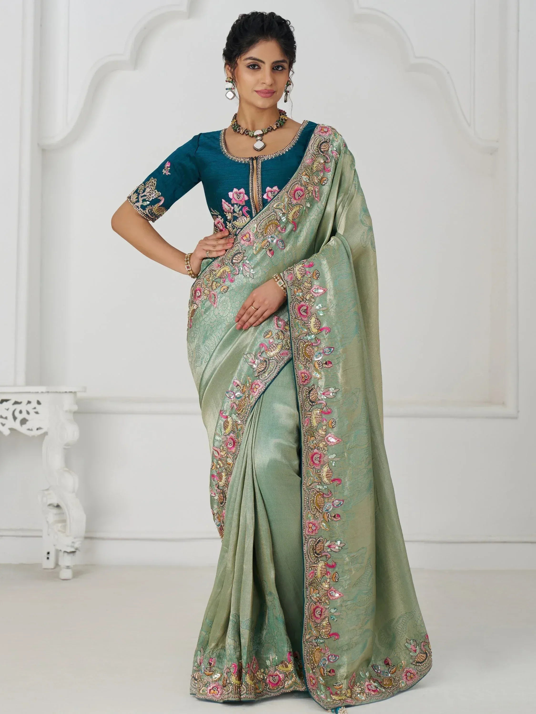 Elegant green saree with floral embroidery and teal blouse, perfect for Indian ethnic occasions.