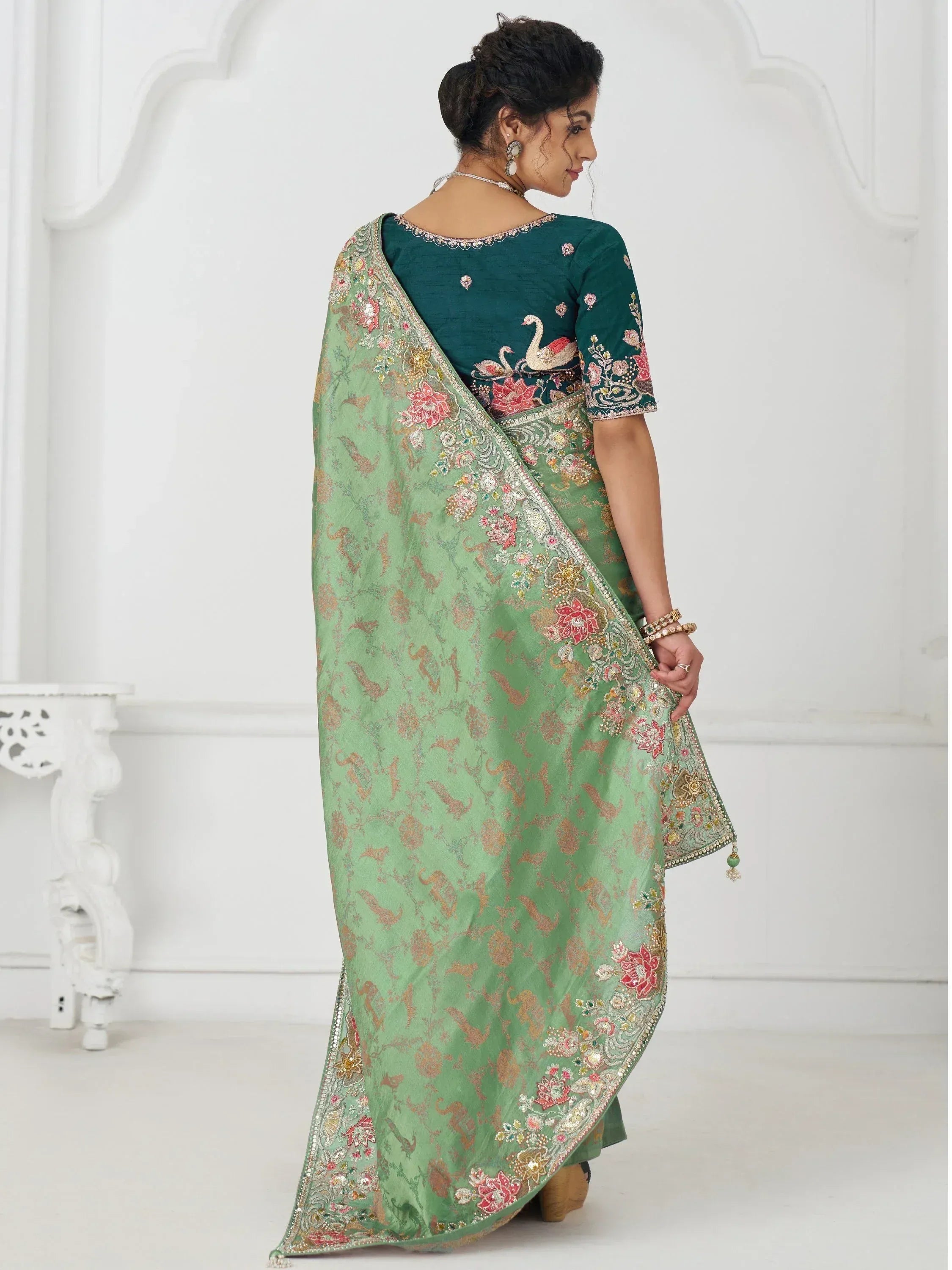 Green embroidered saree with floral and swan motifs, perfect for Indian ethnic wear occasions.