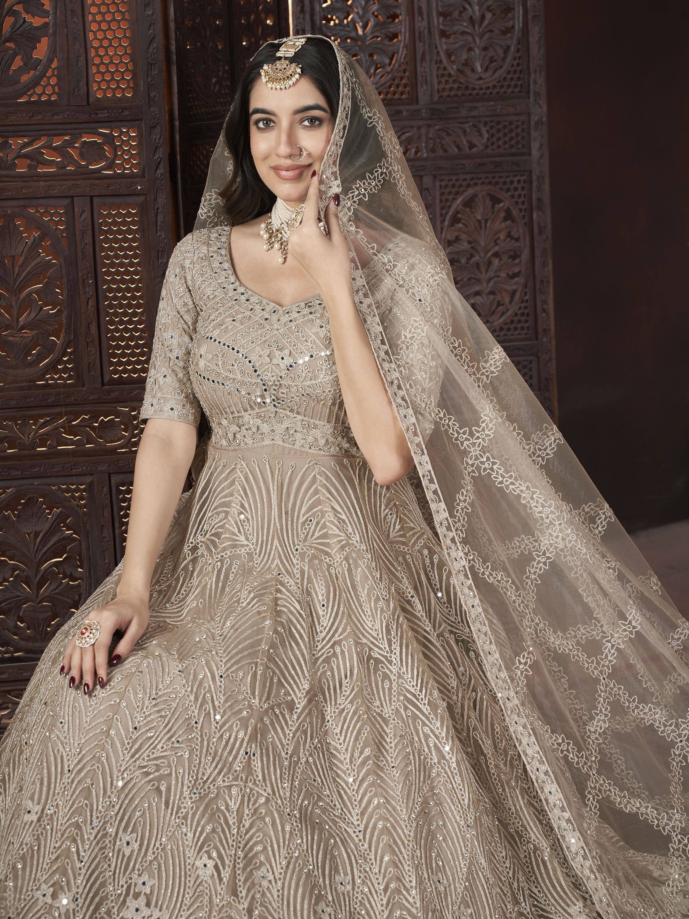 Elegant beige embroidered lehenga choli with sheer dupatta, perfect for Indian weddings and festive occasions.