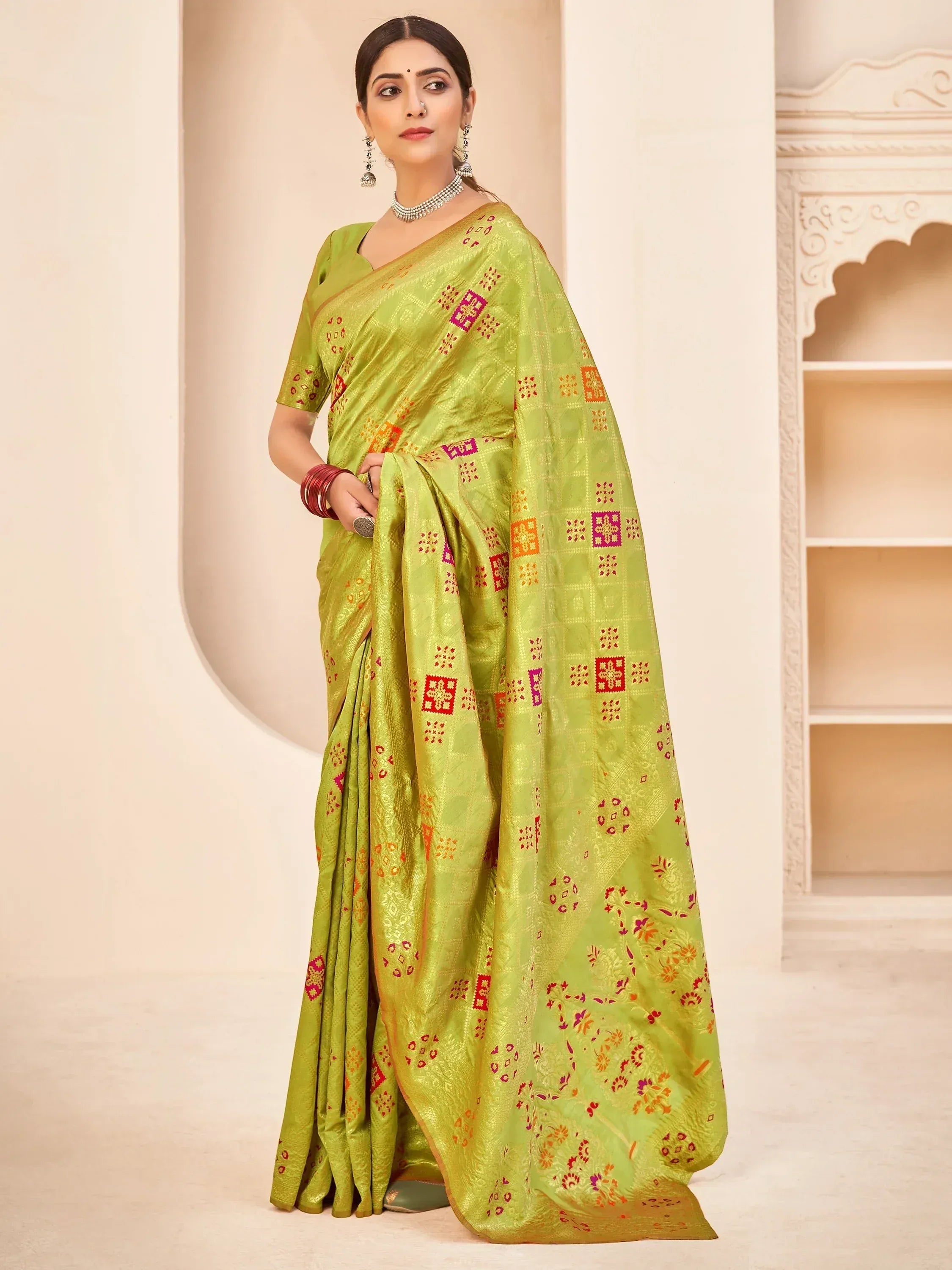 Woman in vibrant green ethnic saree with red and gold geometric print, perfect for Indian occasions