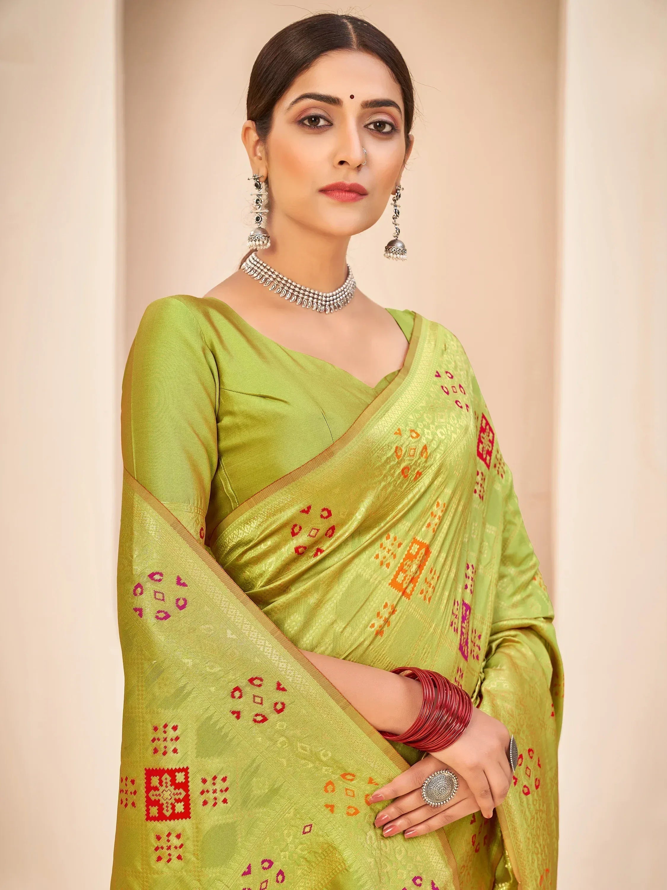 Green ethnic saree with red and orange geometric print, paired with traditional jewelry for Indian wear